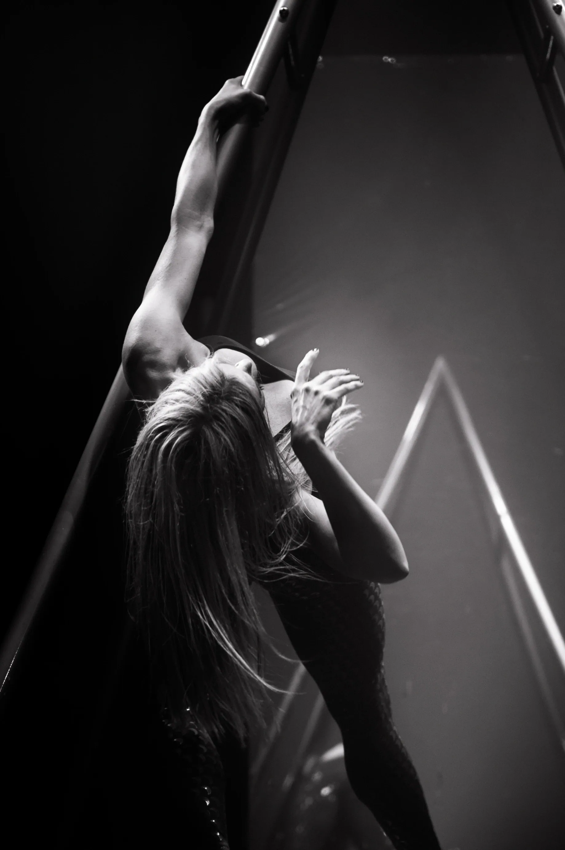 Close view of a performer leaning backward while gripping an aerial strap.