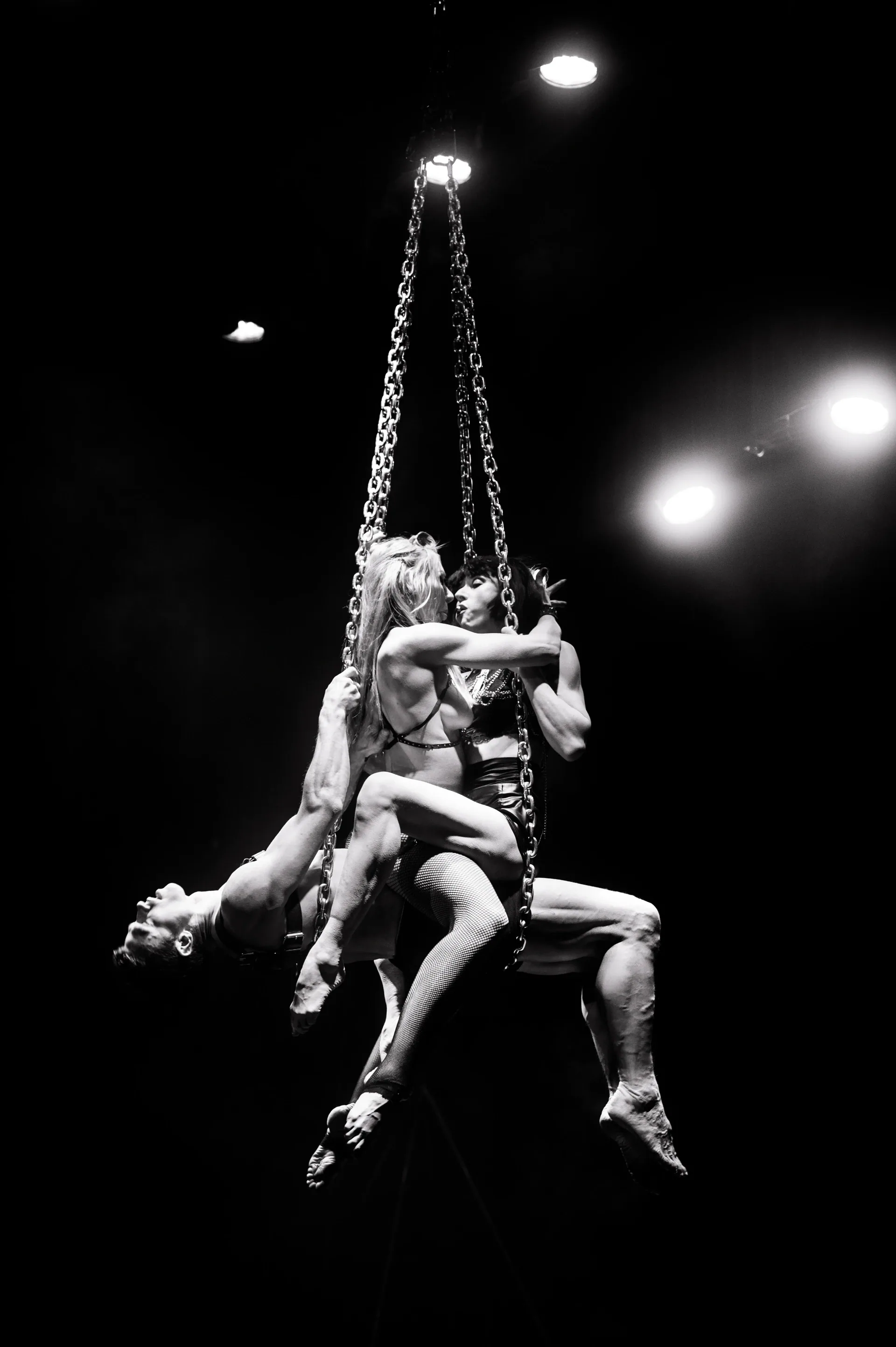 Group of performers cluster together on a suspended chain apparatus.