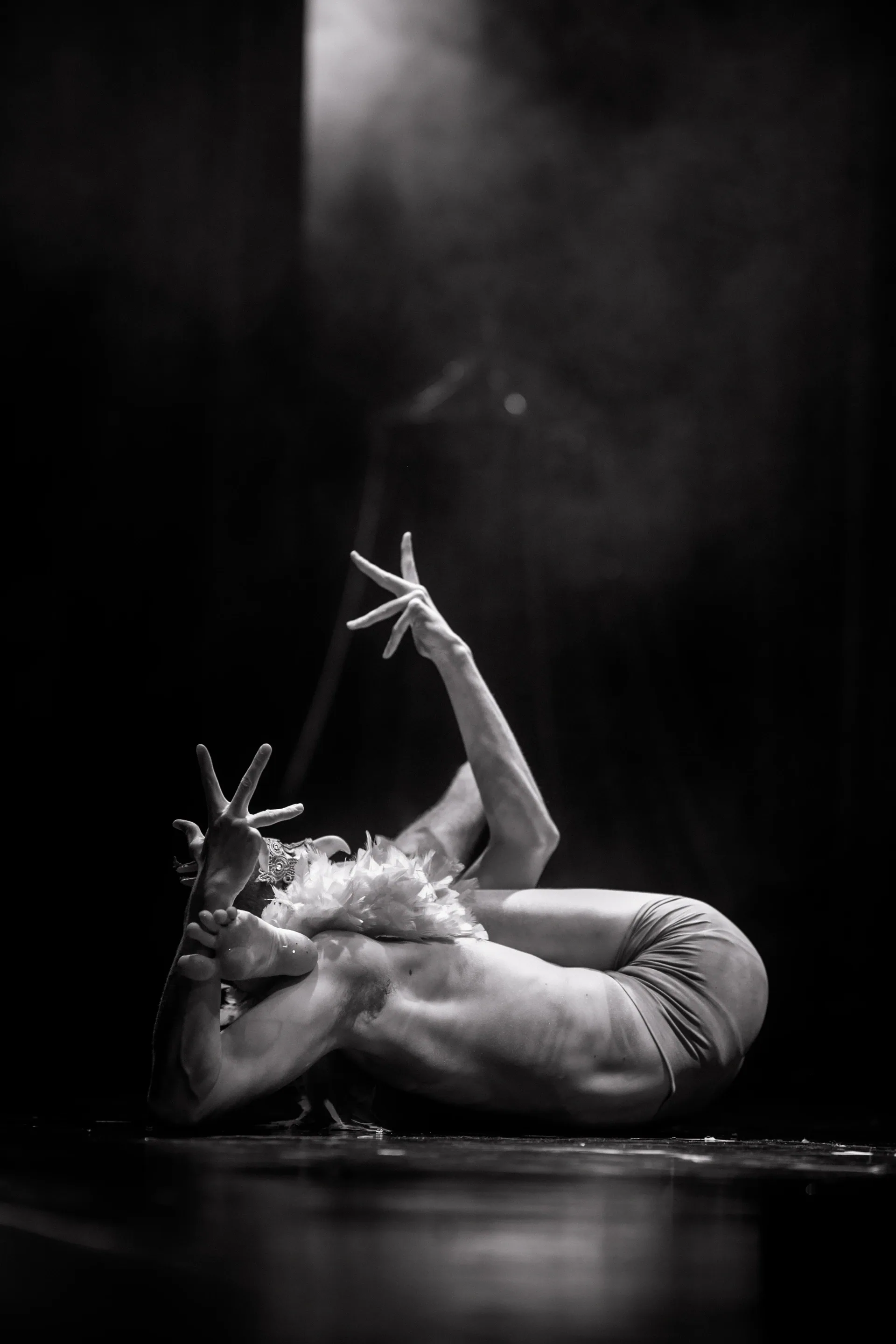 Two floor performers pose together, one lying with both legs raised.