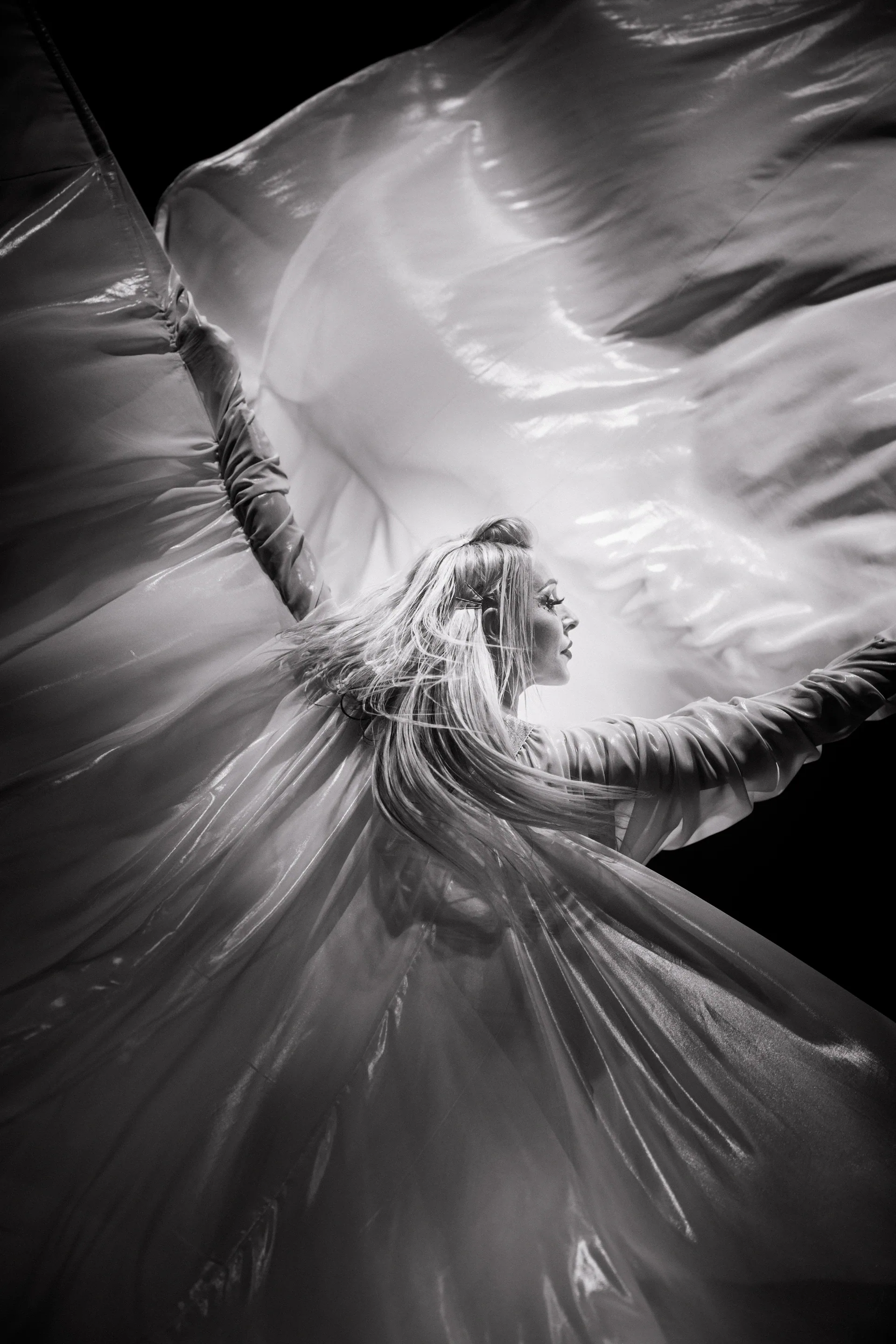 Performer turns while sweeping a large sheet of fabric through the air.