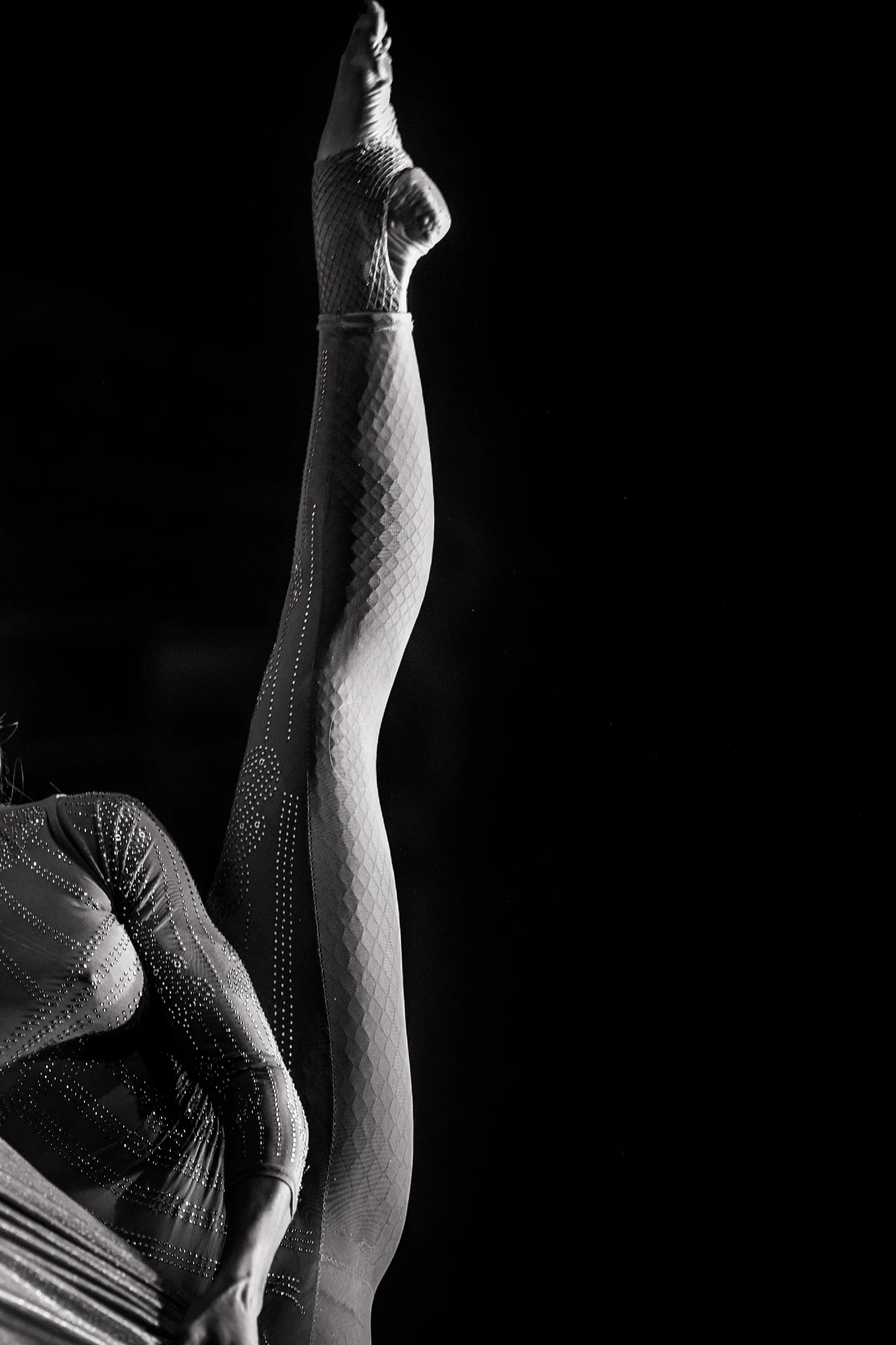 A performer's legs extend vertically above the stage beside draped fabric.