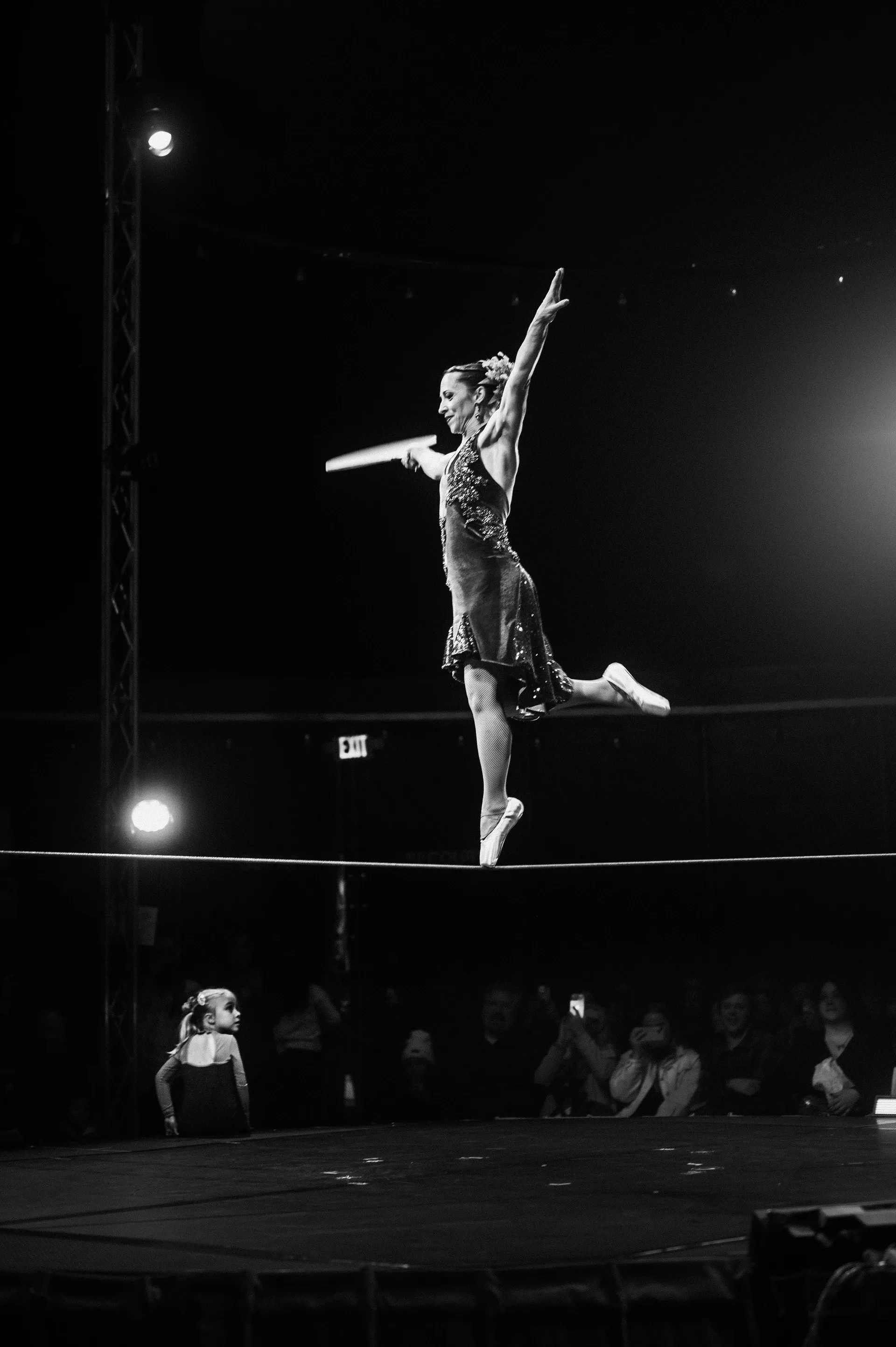 Acrobat leaps above a tightrope with a long balancing pole.