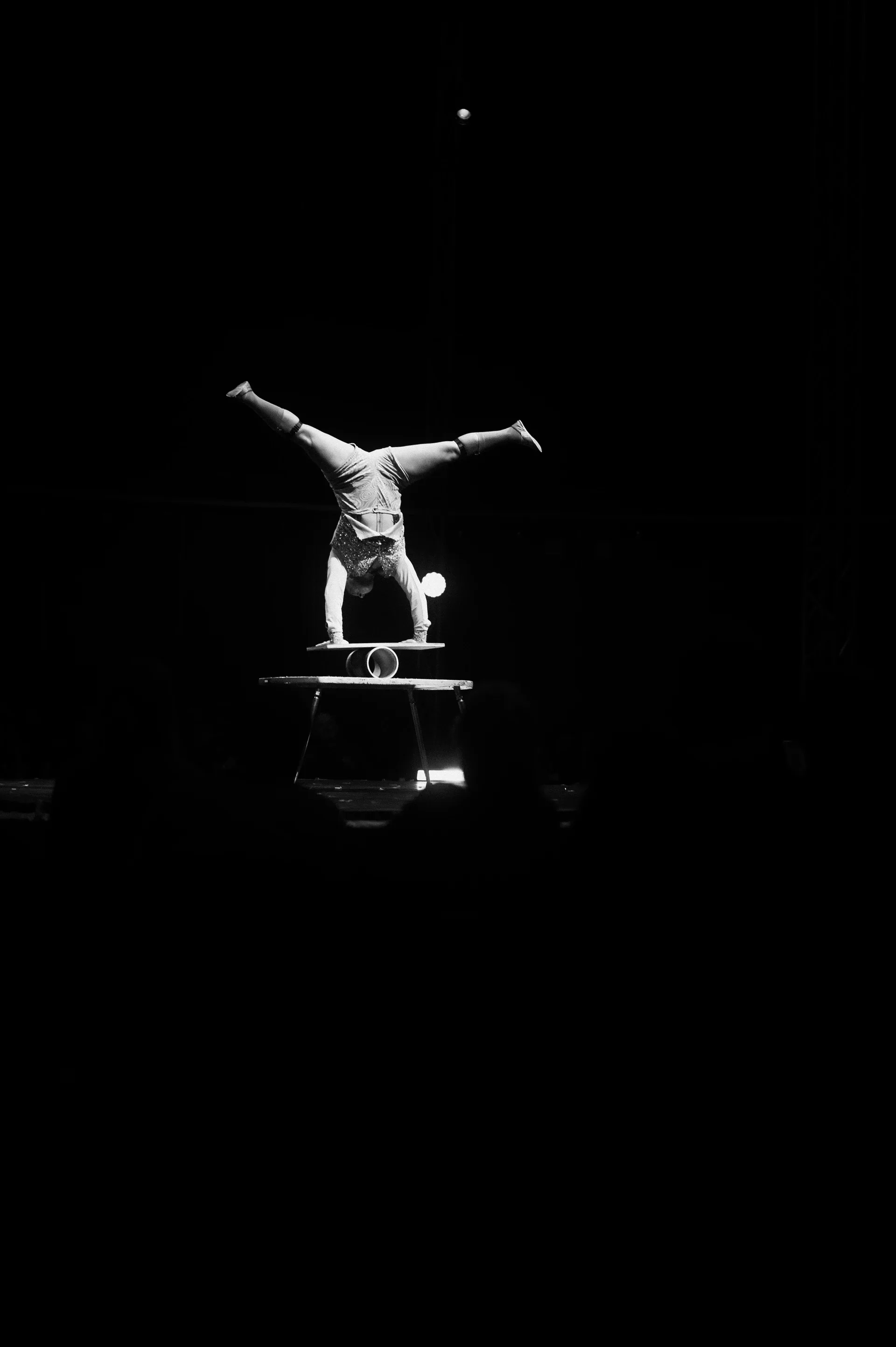 Distant performer holds a handstand on a small raised platform.