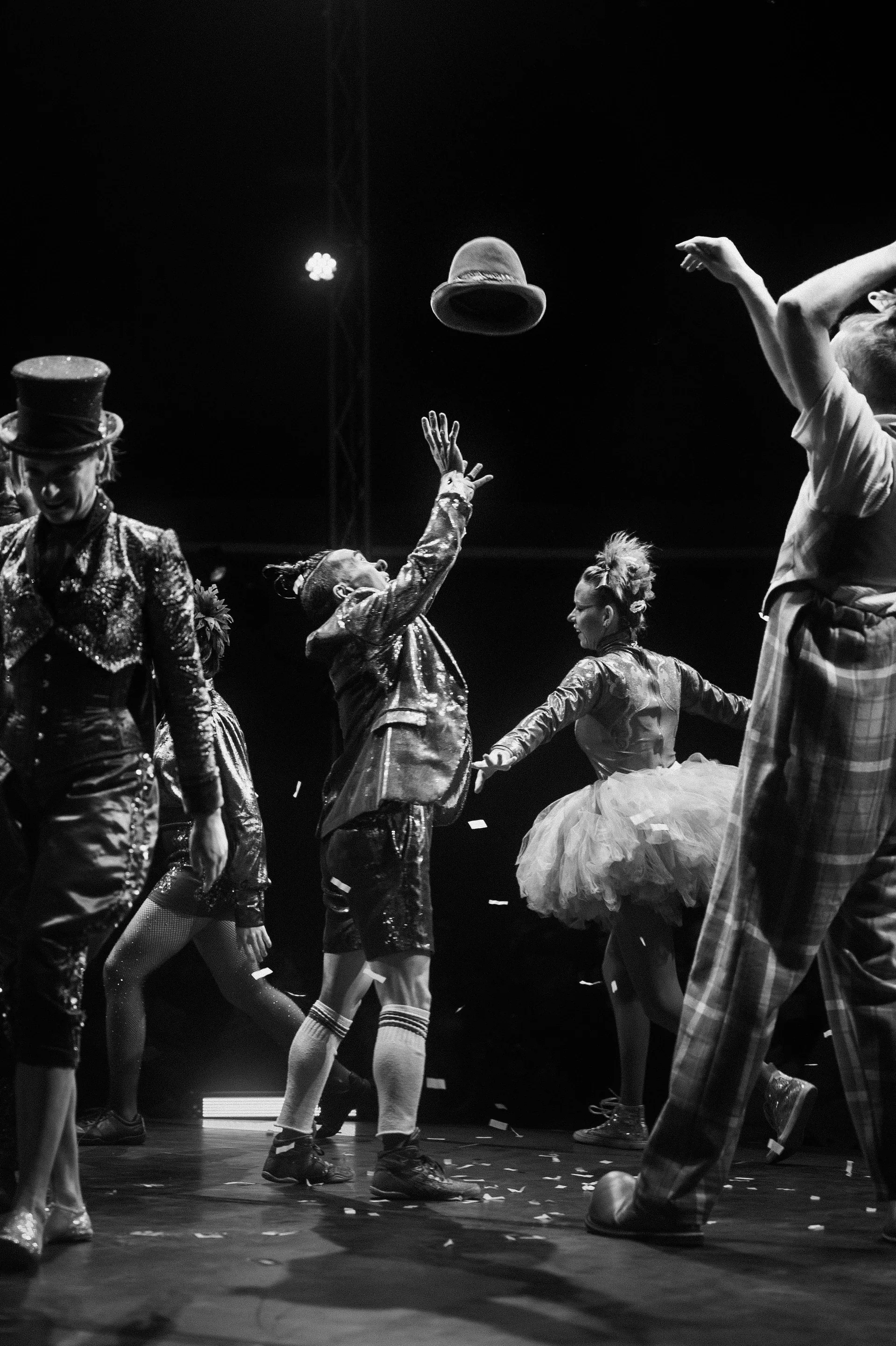 Costumed ensemble tosses hats above the stage.