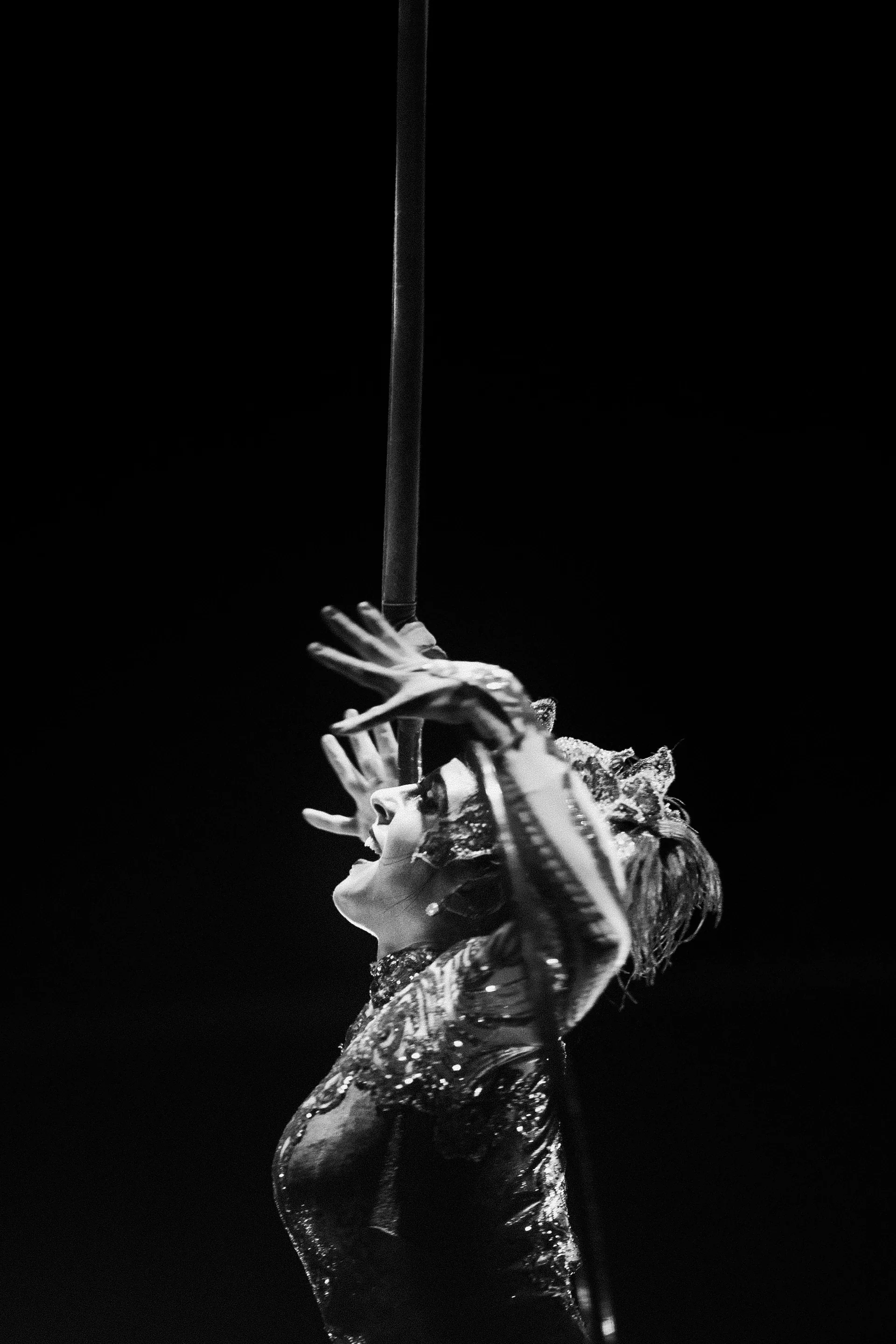 Costumed performer tilts the head with one hand raised beside the face.