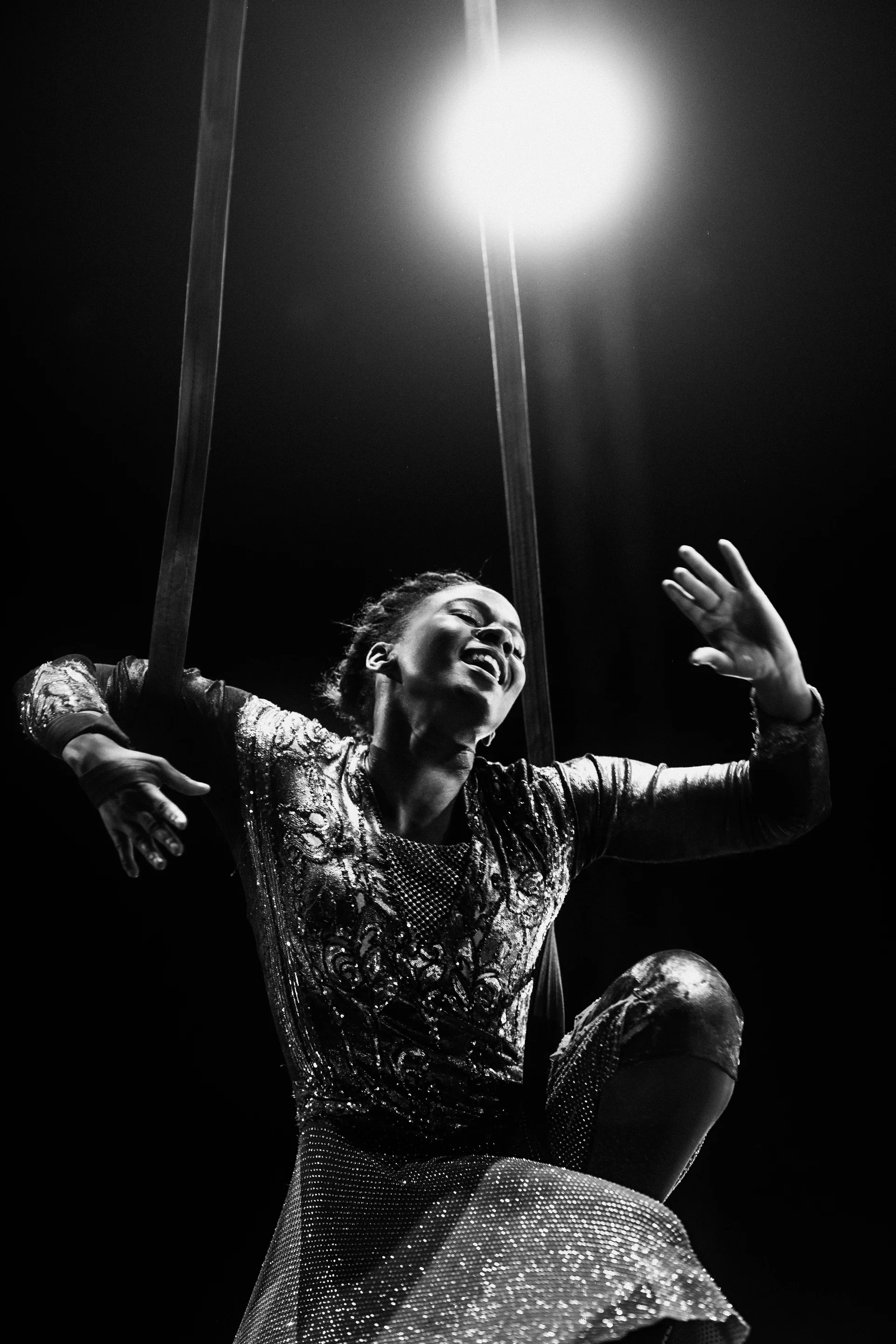 Performer kneels on a glittering prop with both hands raised.