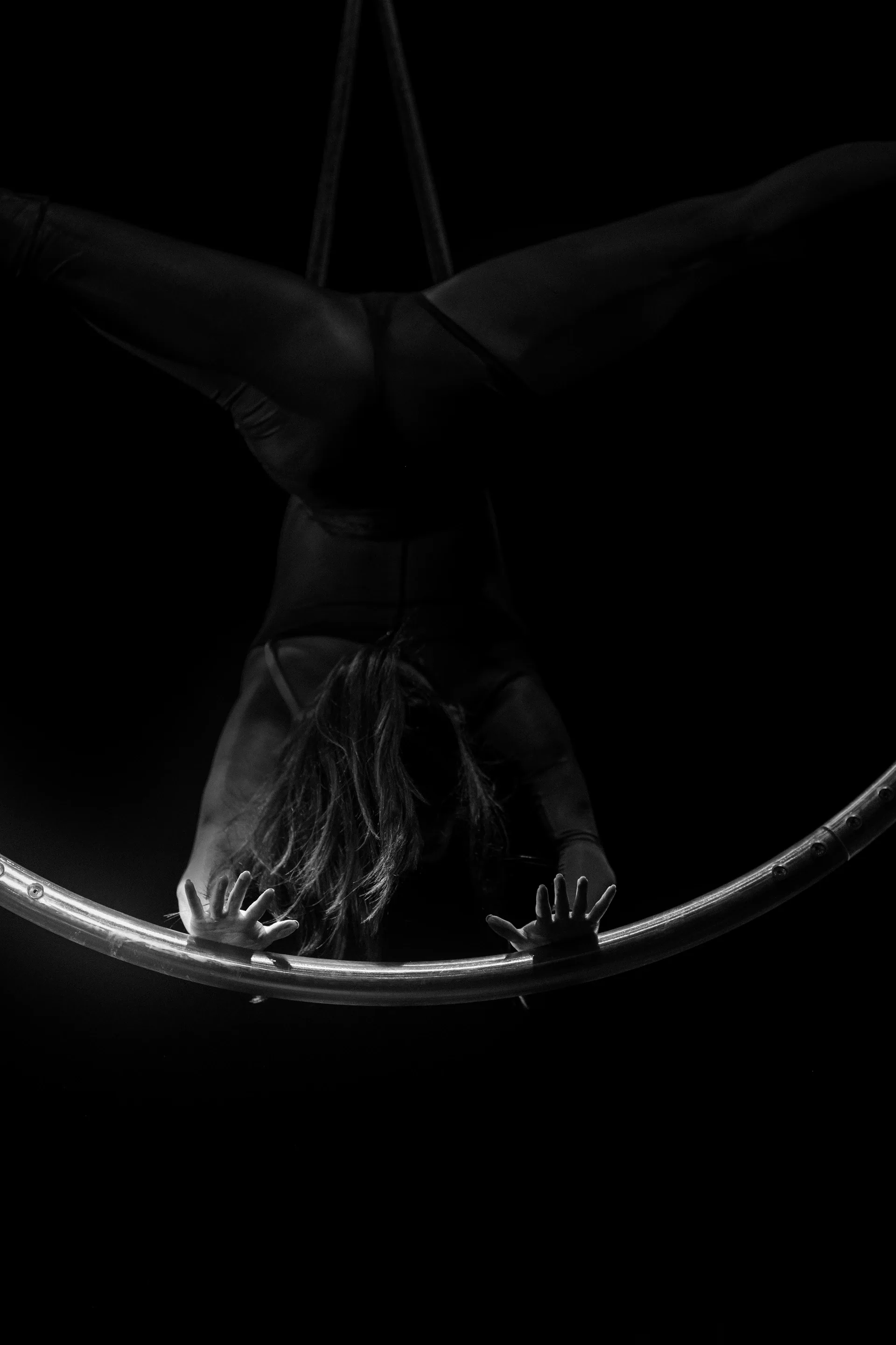 Close view of two hands gripping the underside of an aerial hoop.