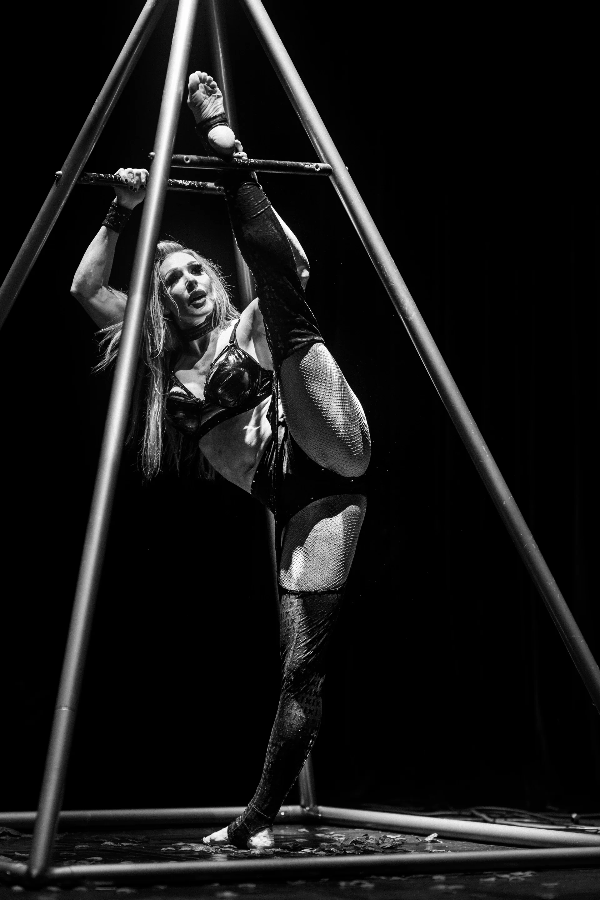 Performer stands inside a large triangular metal apparatus.