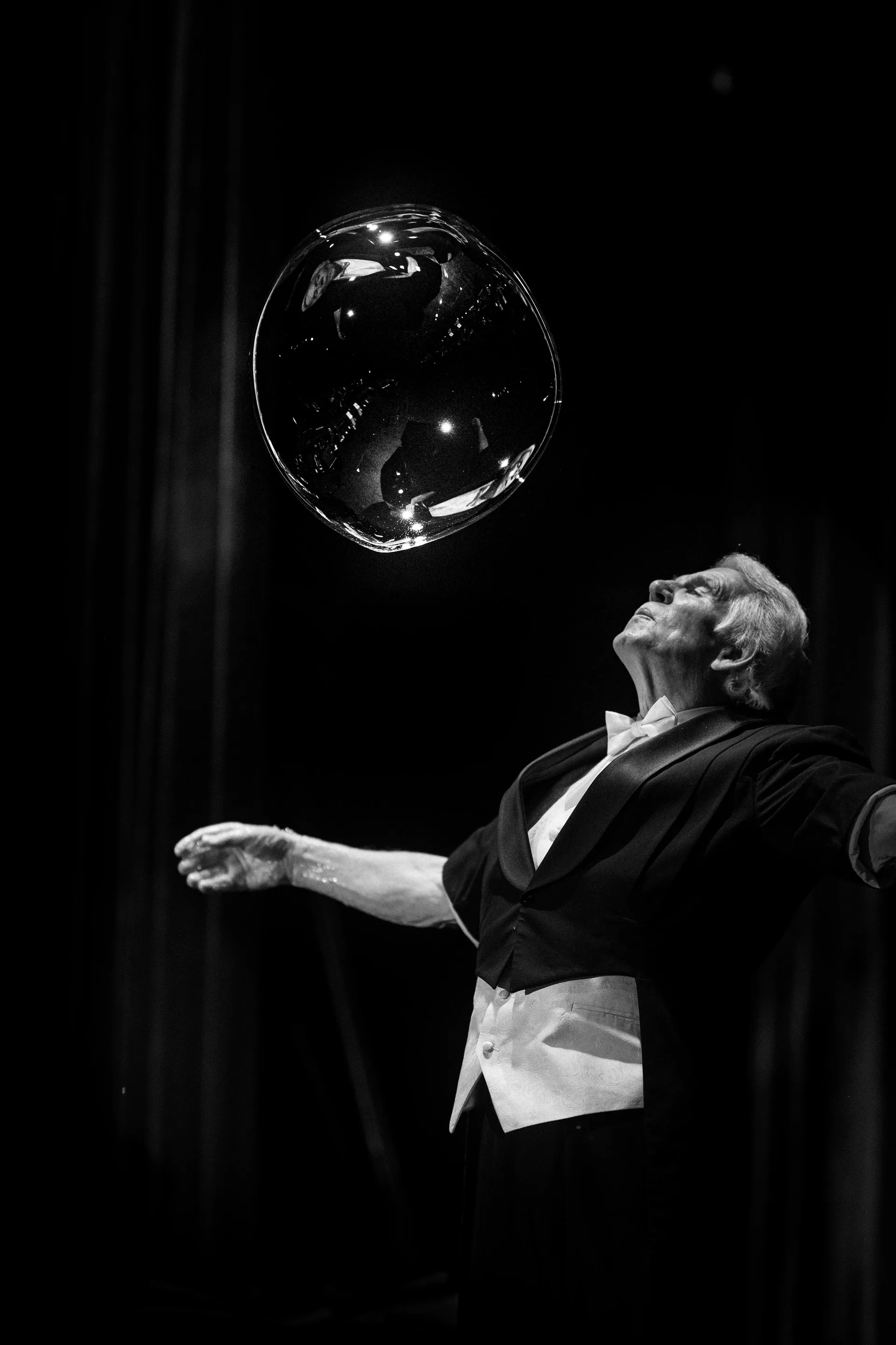 Performer balances a large clear bubble above an outstretched hand.