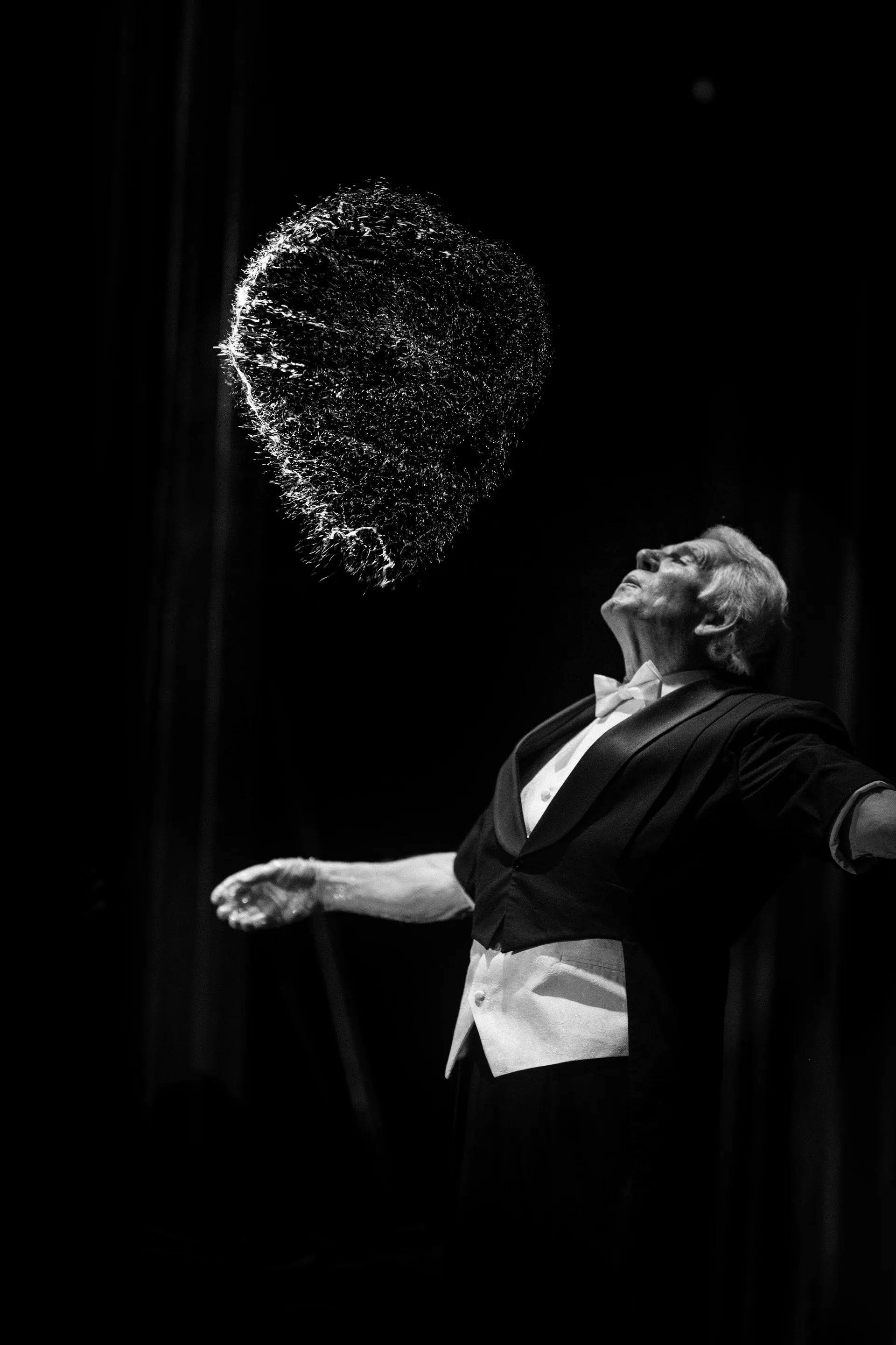 Performer tilts the head beneath a burst of fine droplets.