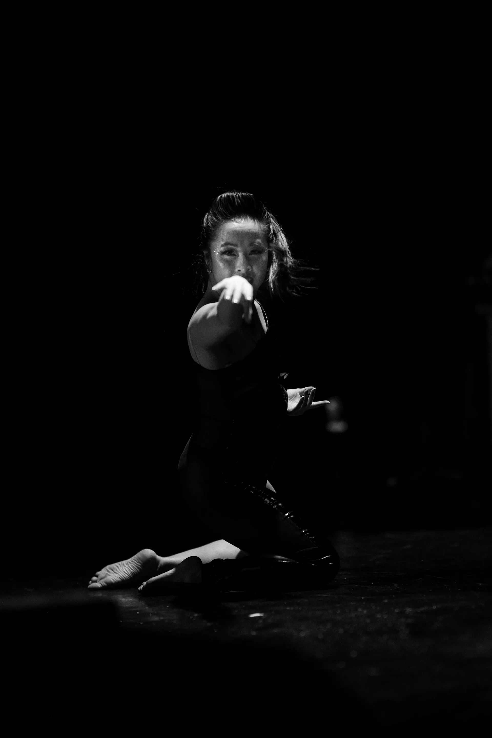 Seated performer holds a microphone with the face partly in shadow.