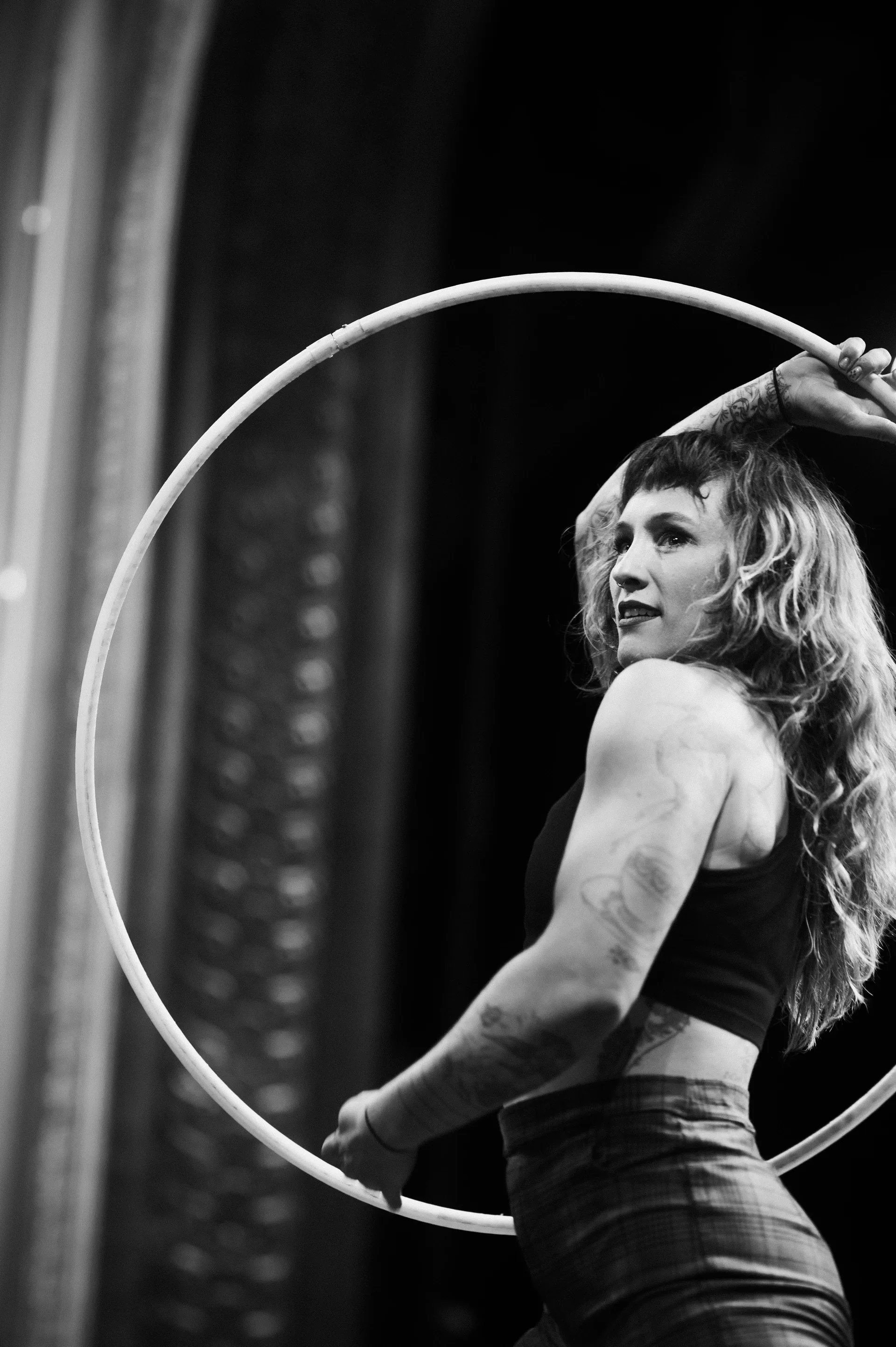 Performer holds a large hoop upright and looks over one shoulder.