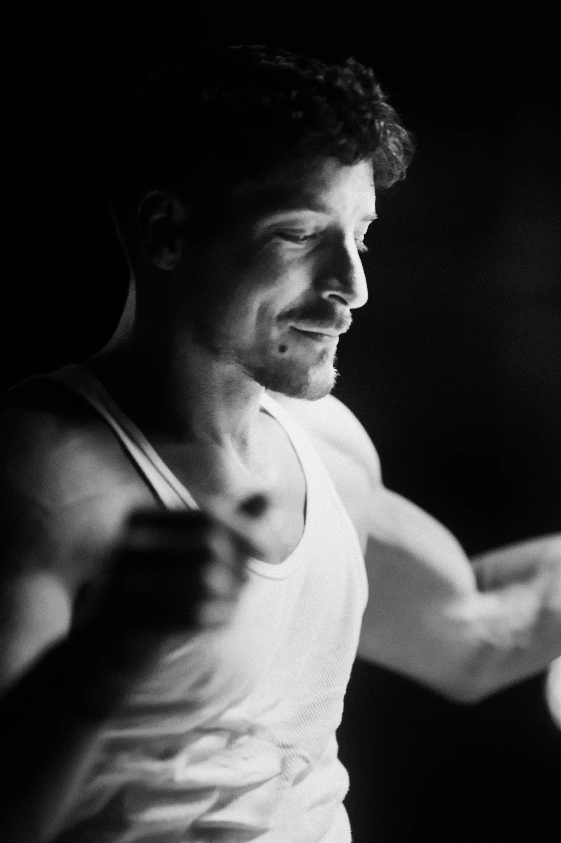Performer in a sleeveless top stands under bright stage lighting.