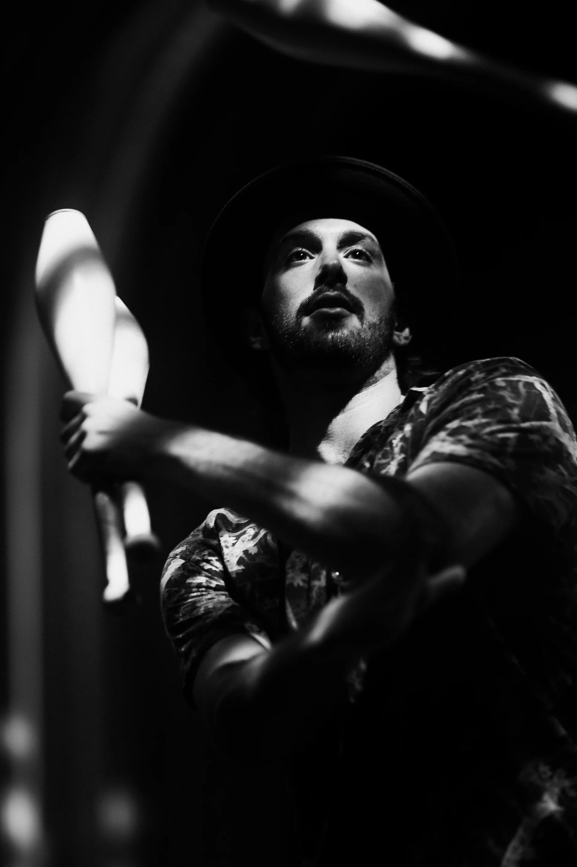 Bearded performer in a patterned shirt leans near the edge of the stage.