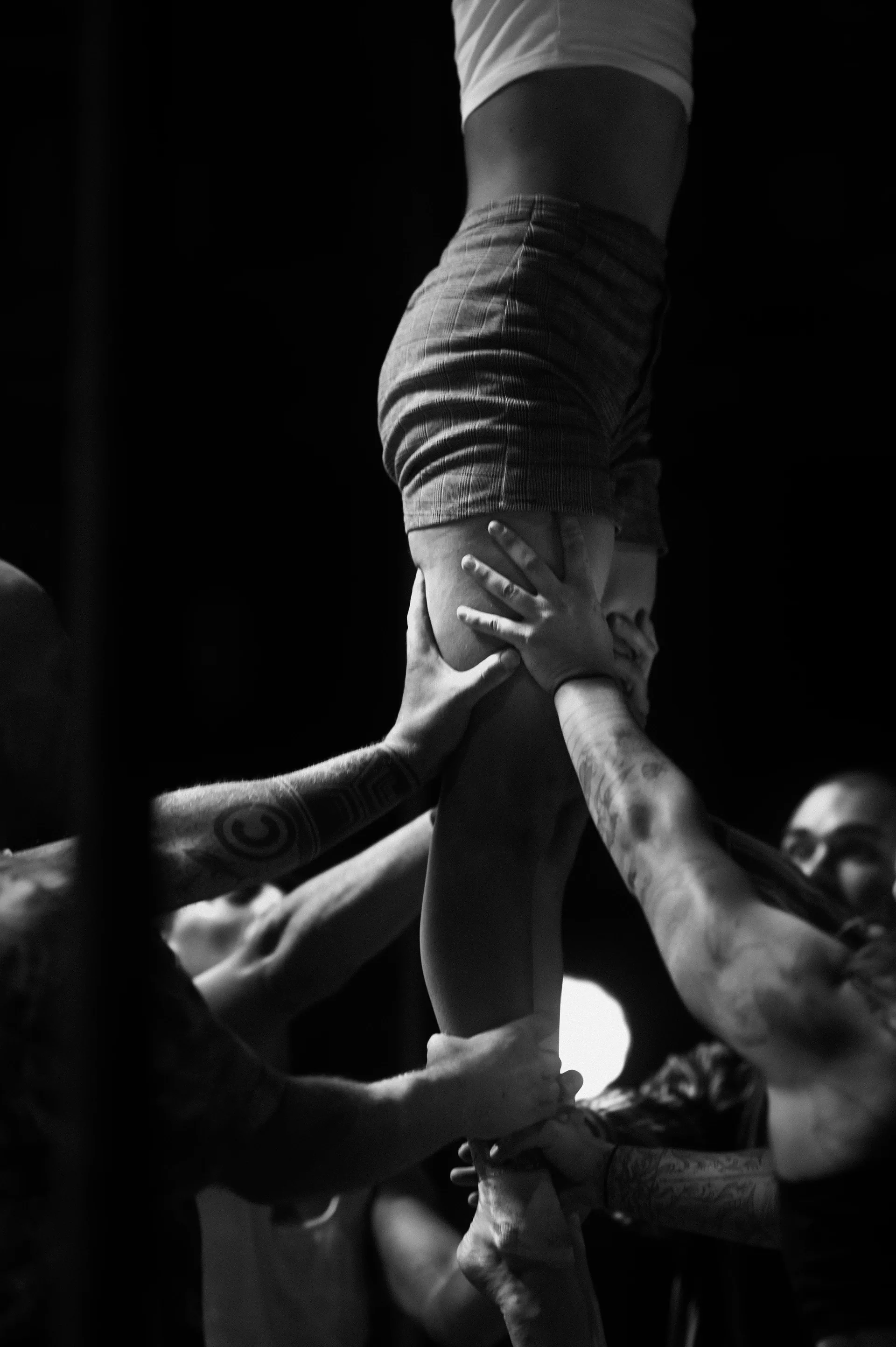 Several hands support the legs of an elevated performer.