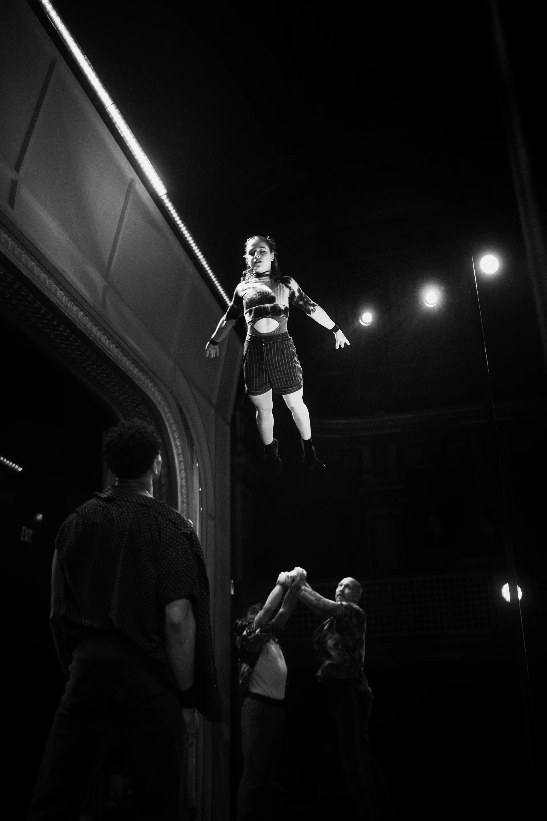 Acrobat balances high above supporting performers near the stage edge.