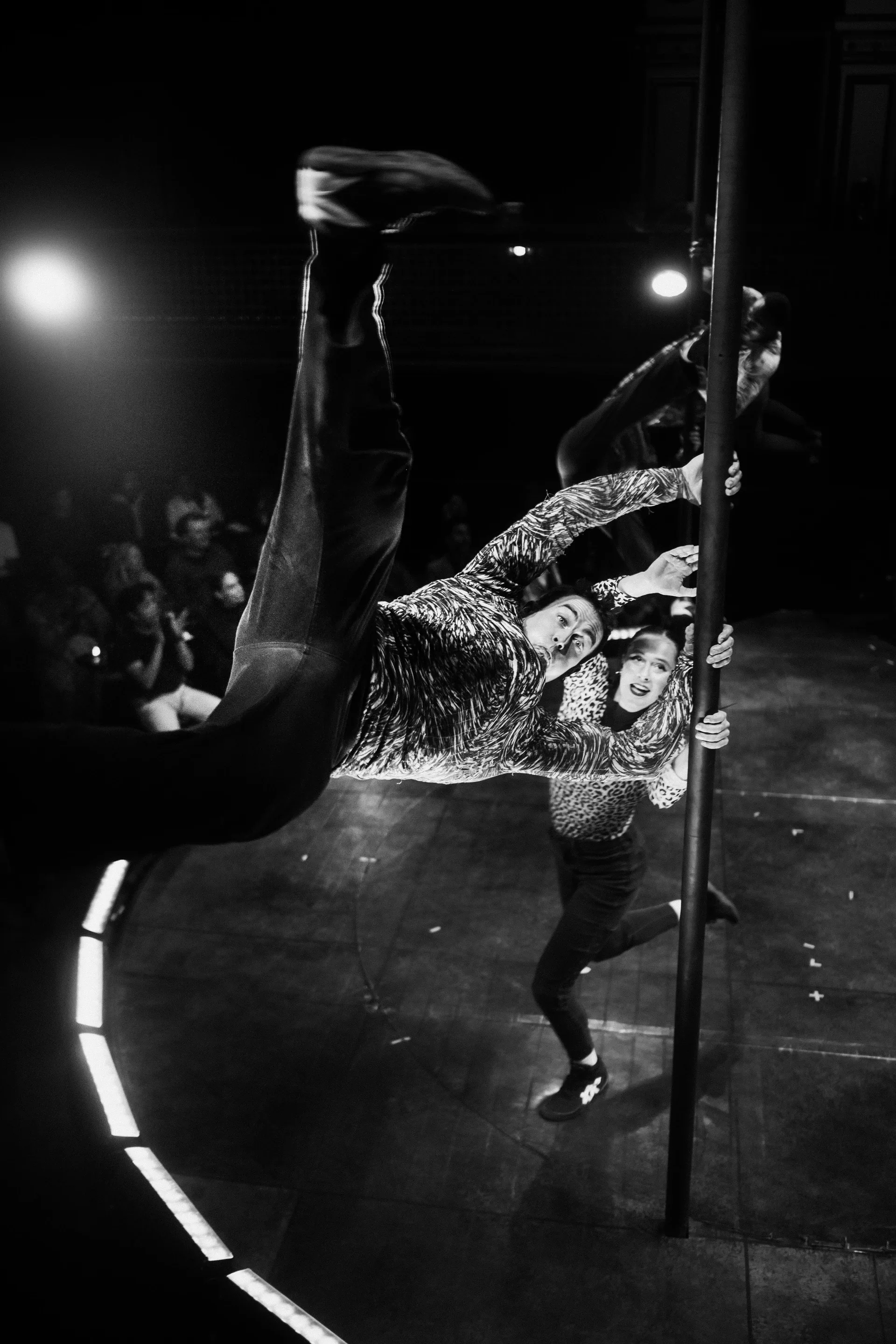 Performer in a reflective costume slides low with one leg extended.