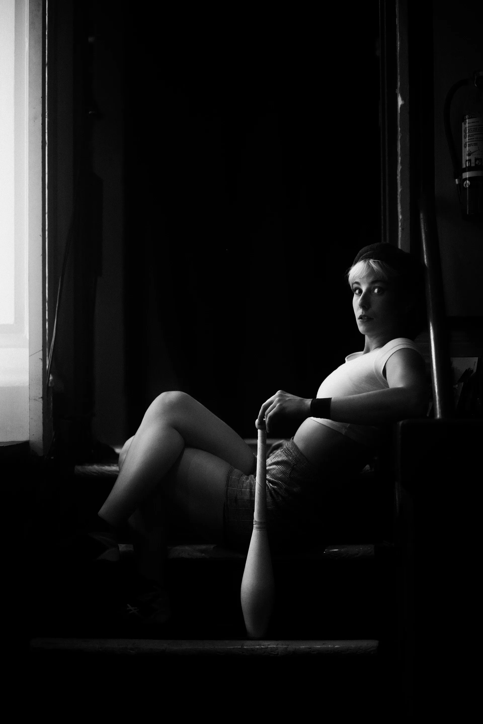 Performer sits alone behind a side curtain with legs extended.