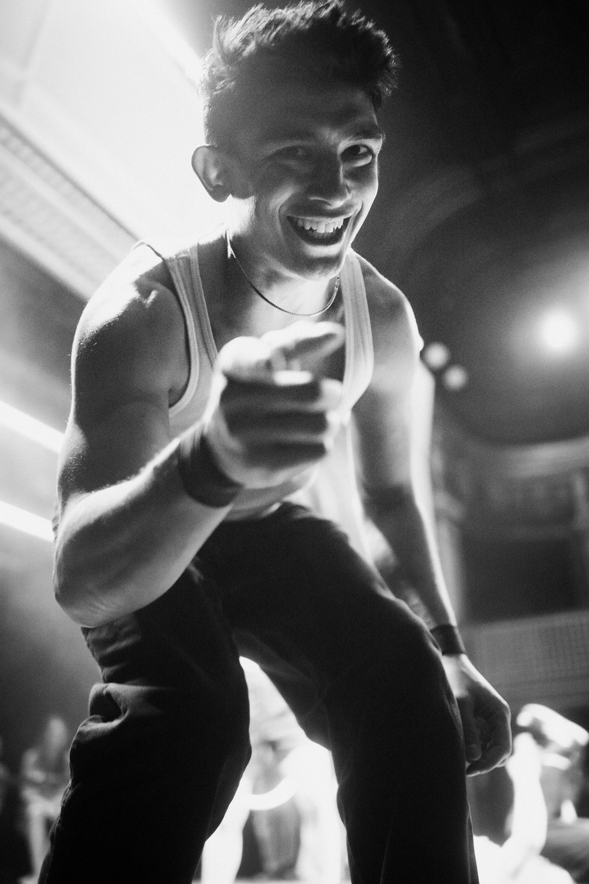 Smiling performer crouches near the stage edge and points forward.