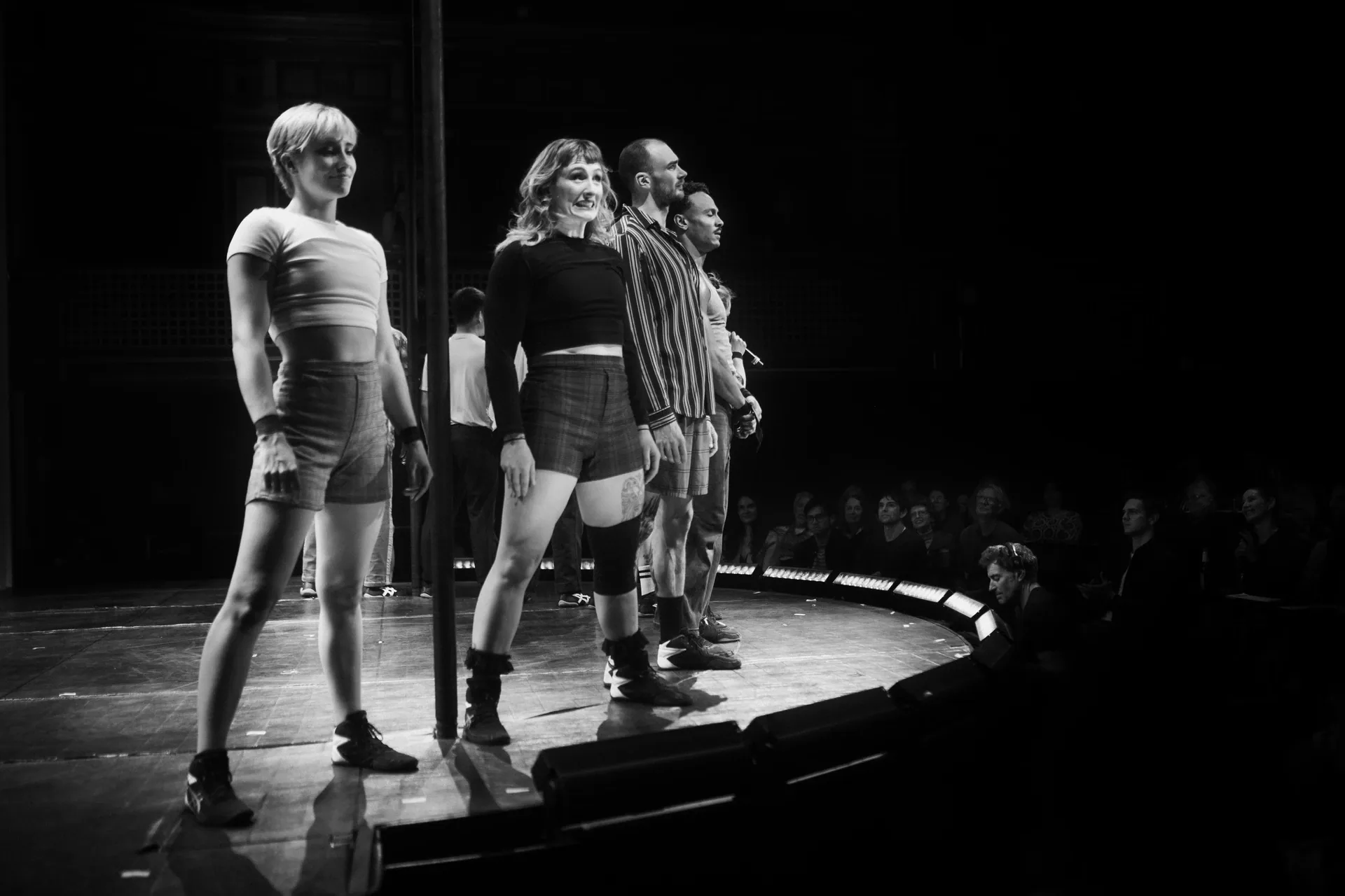 Four performers stand in a line facing the audience.