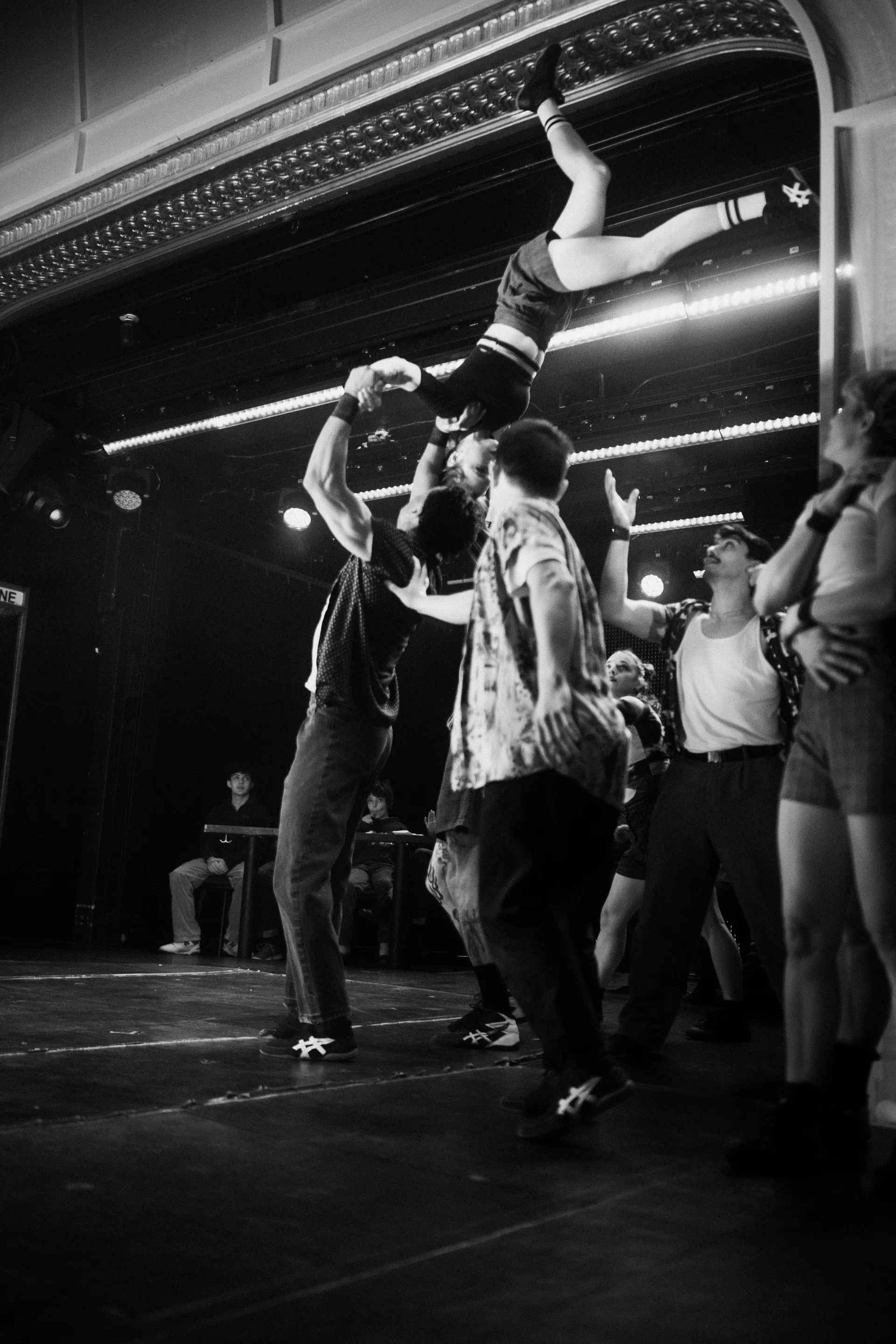 Ensemble lifts a performer horizontally above their heads.