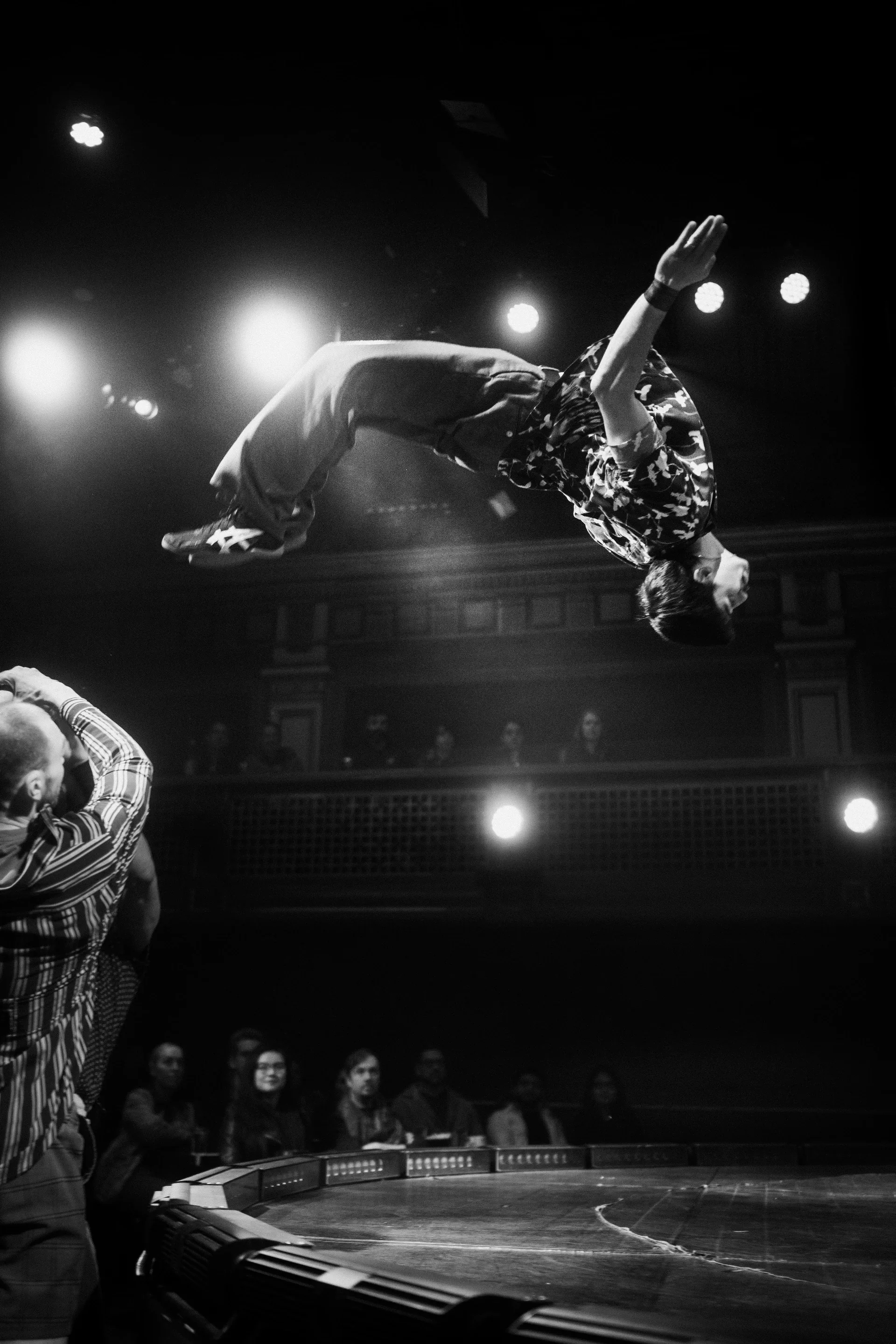 Acrobat flips high above a waiting partner.