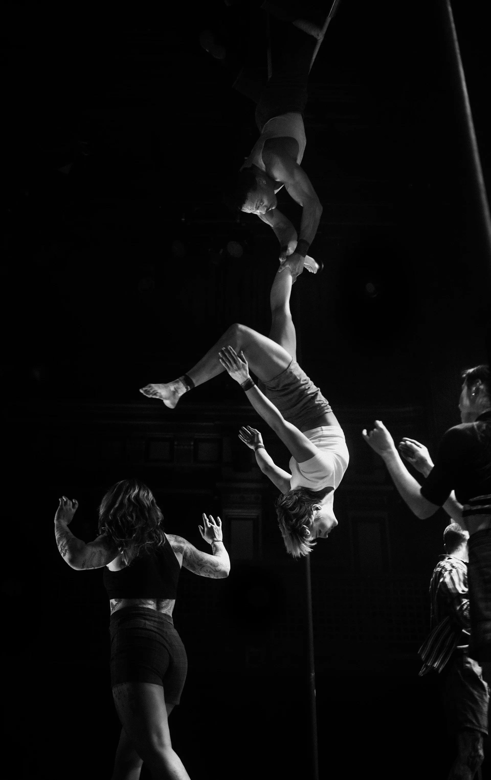 Acrobat flips above the raised hands of an ensemble.