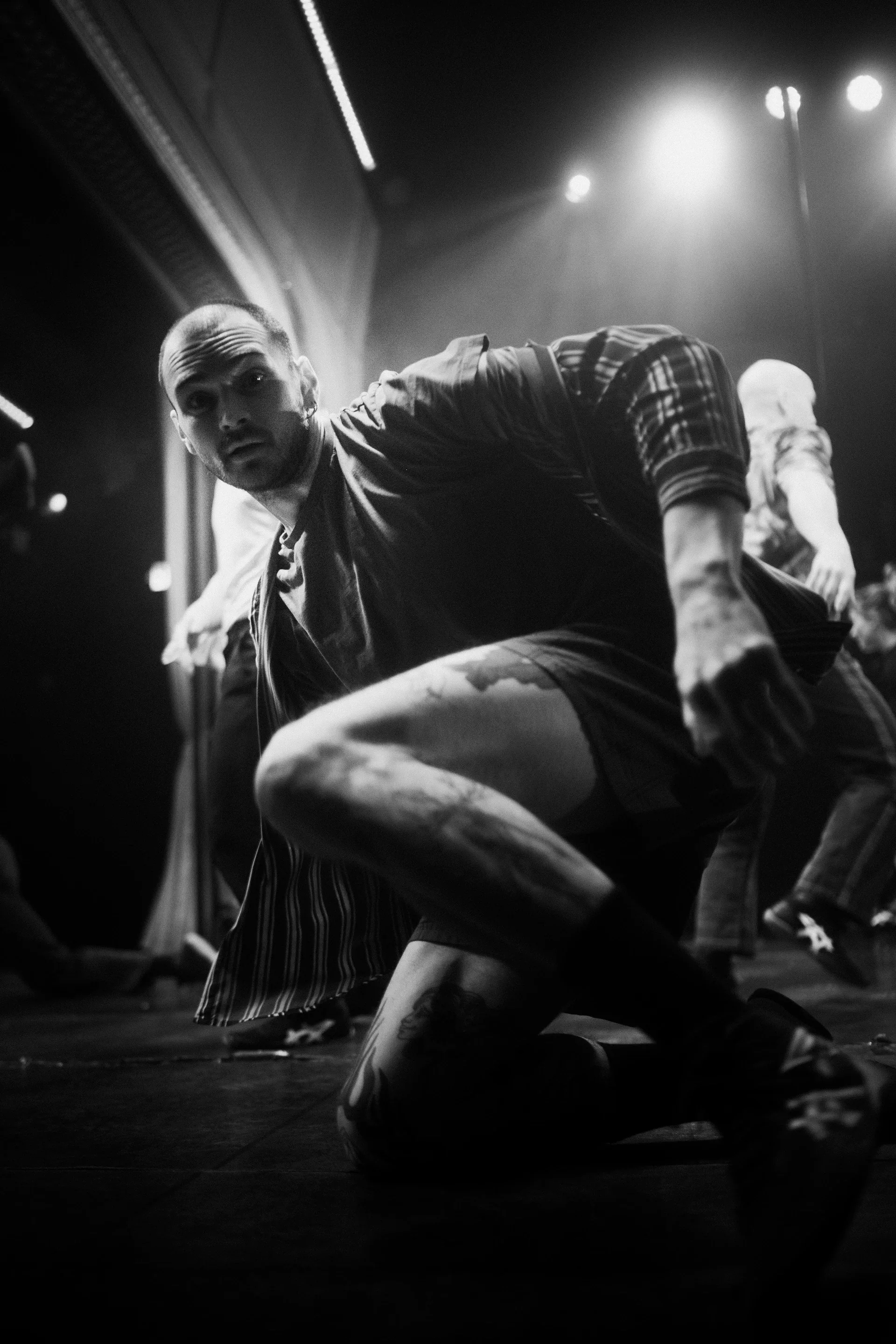 Performer crouches with one leg extended as others stand behind.