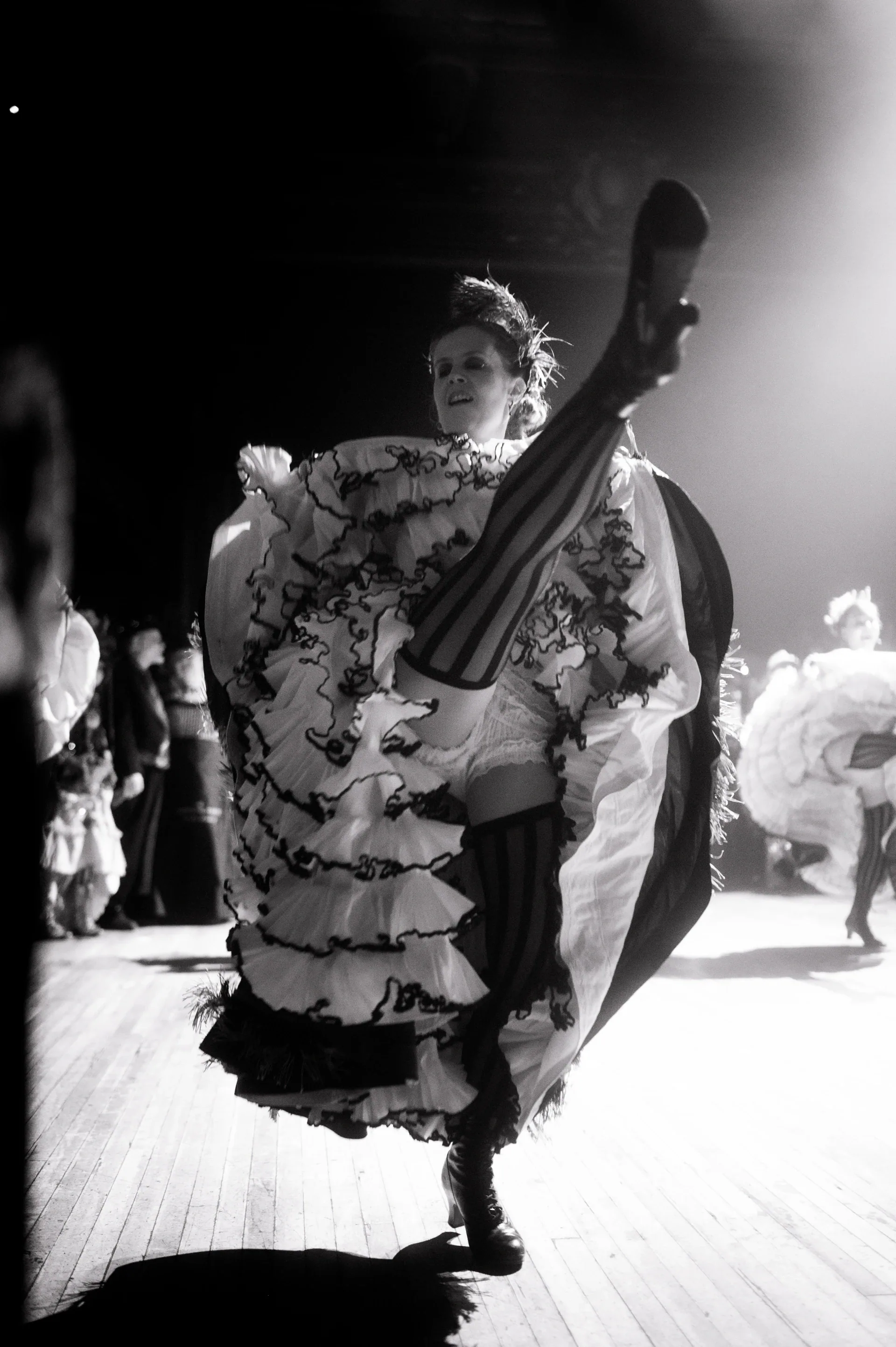 Dancer lifts a ruffled skirt high while turning on the floor.