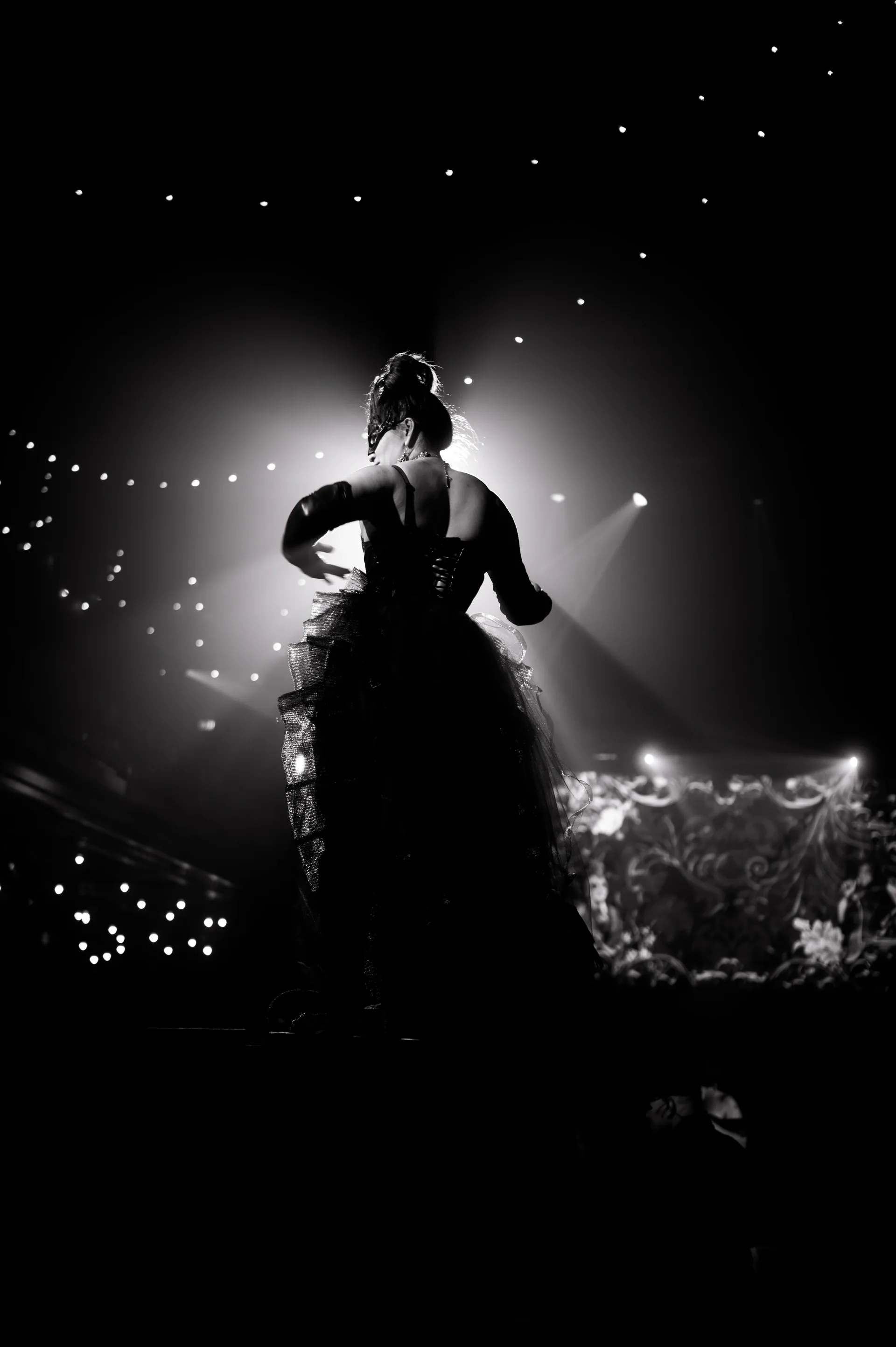 Performer stands before a crowd beneath strings of lights.