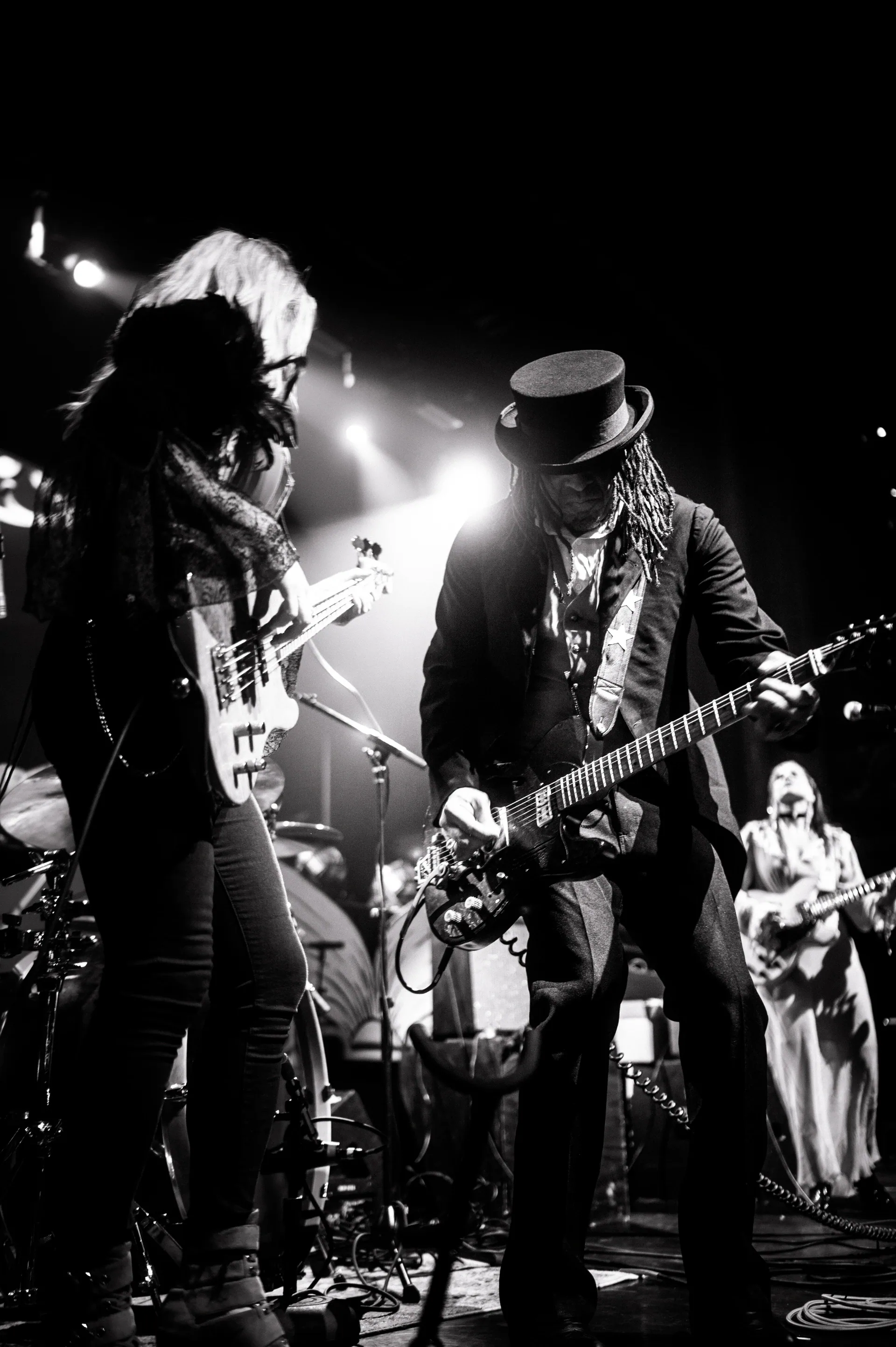 Guitarist and singer perform with a band on a crowded stage.