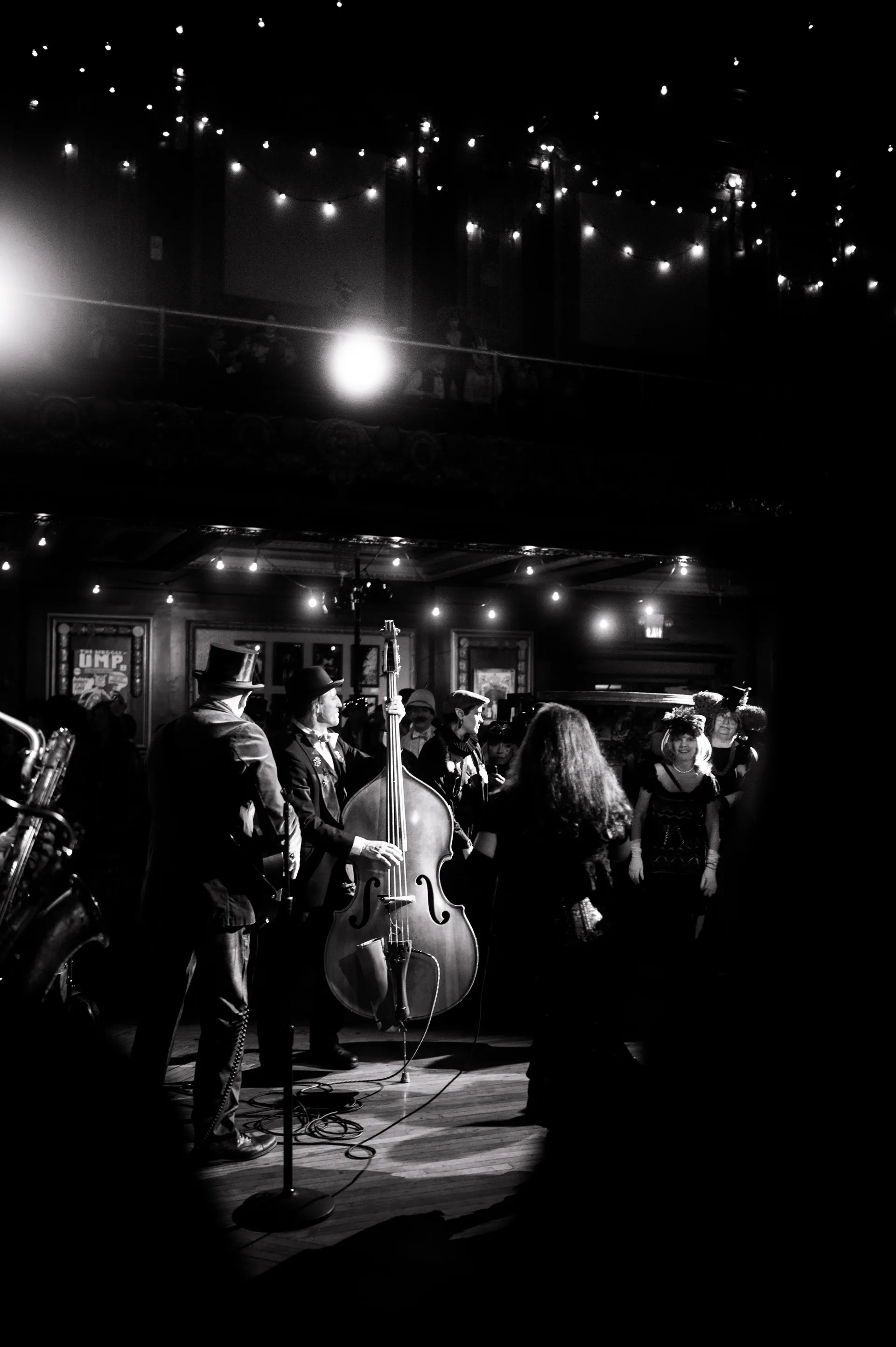 Band performs onstage beneath strings of small lights.