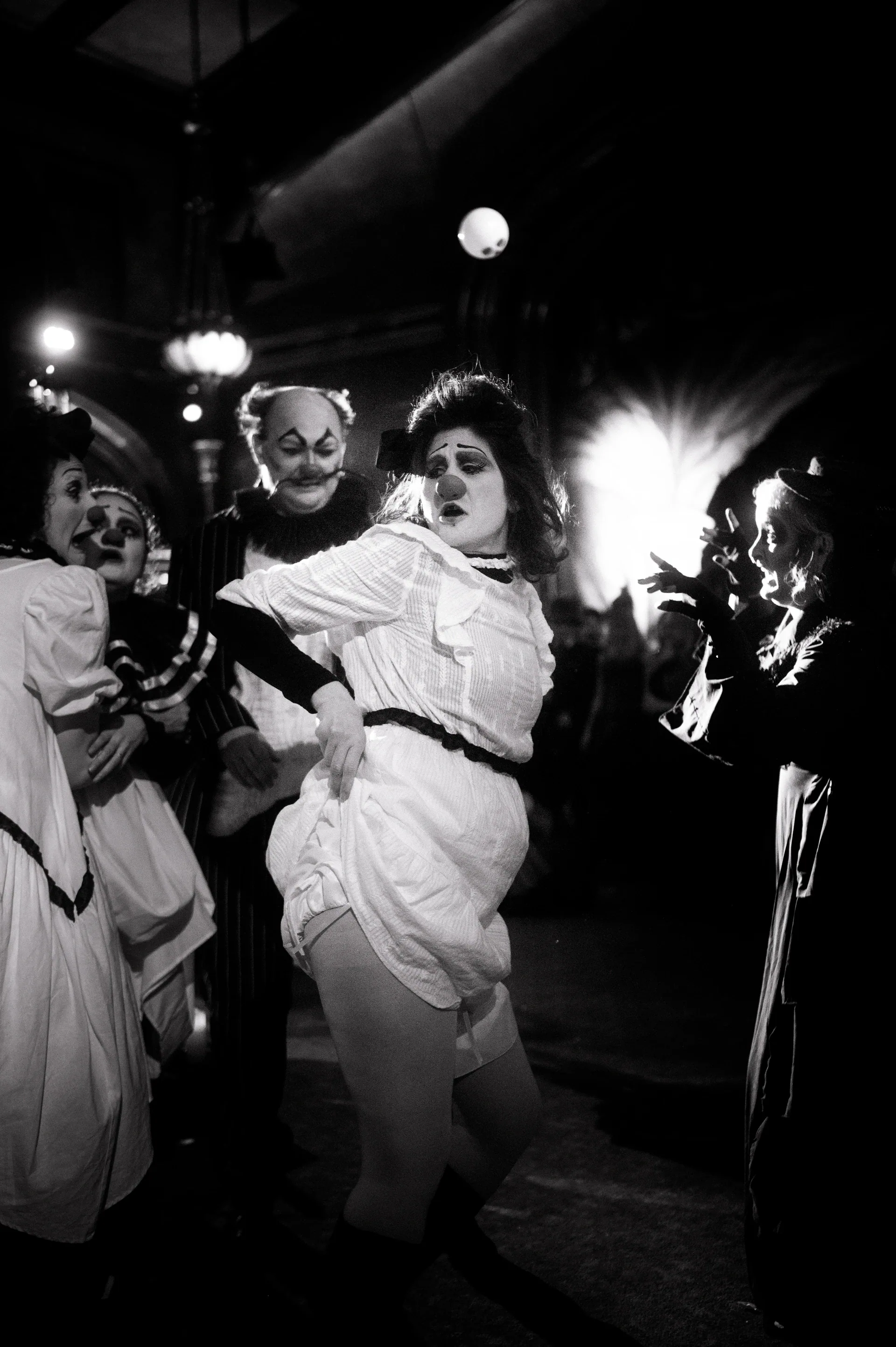 Performer in a light dress leans backward while others dance nearby.