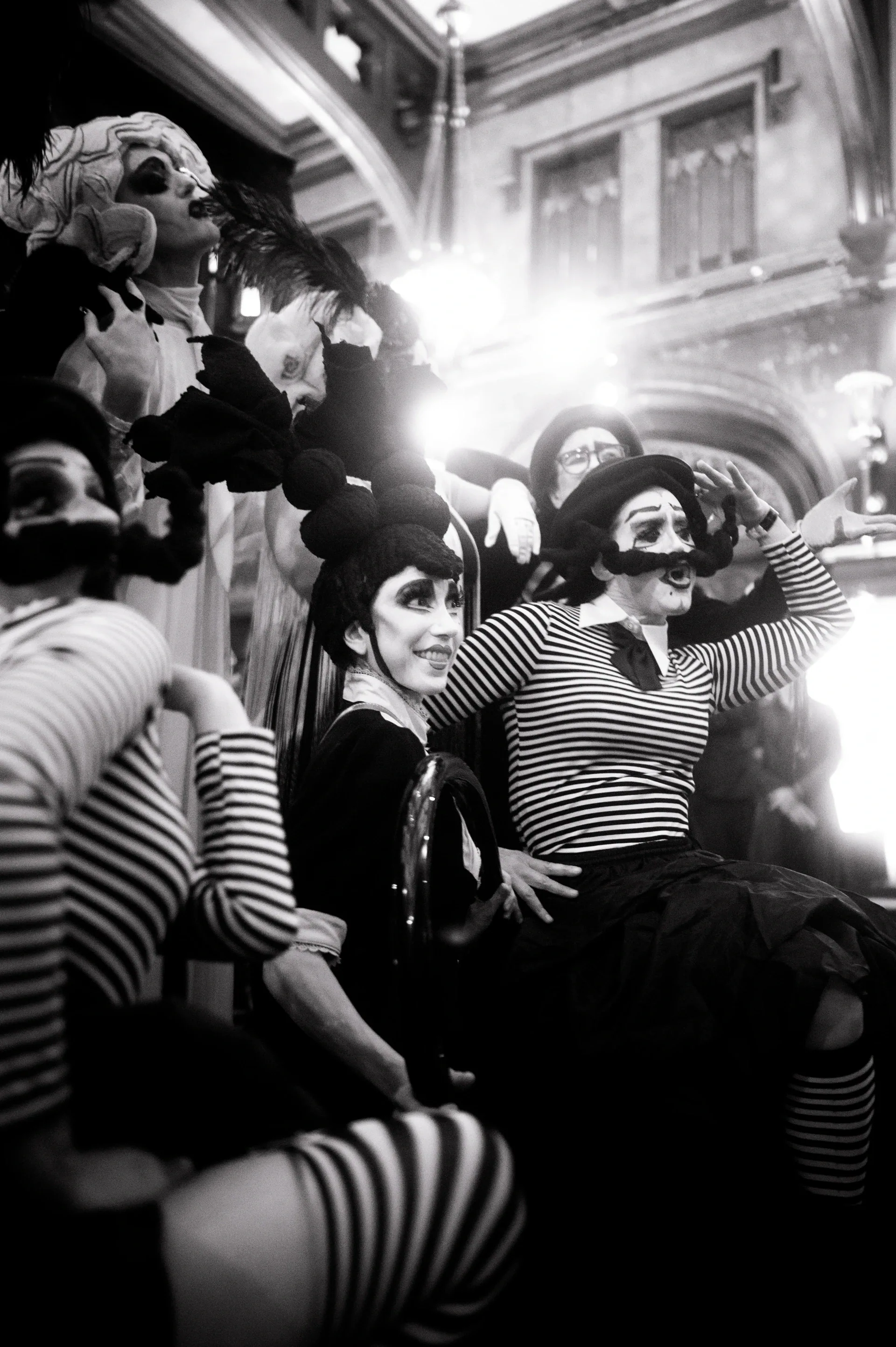 Mime-costumed performers gather beside a standing crowd.