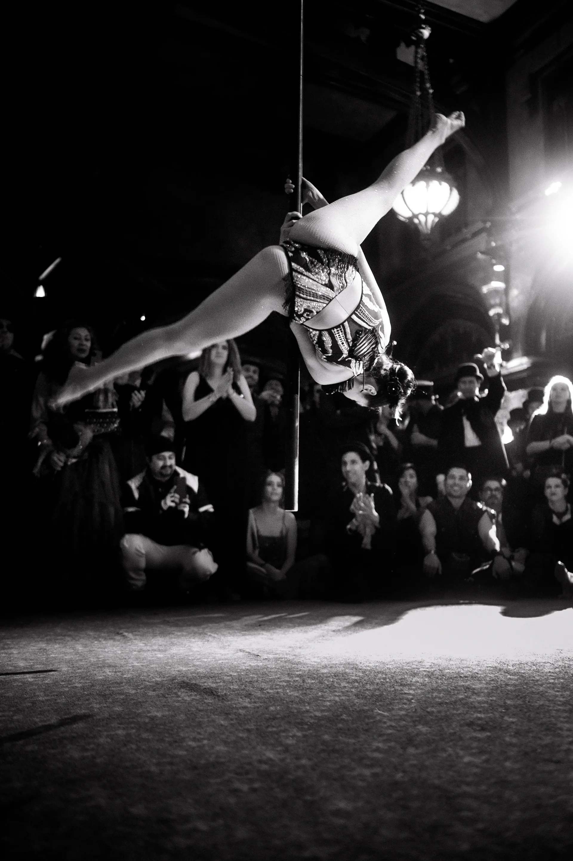 Acrobat extends horizontally above the audience from an aerial rope.