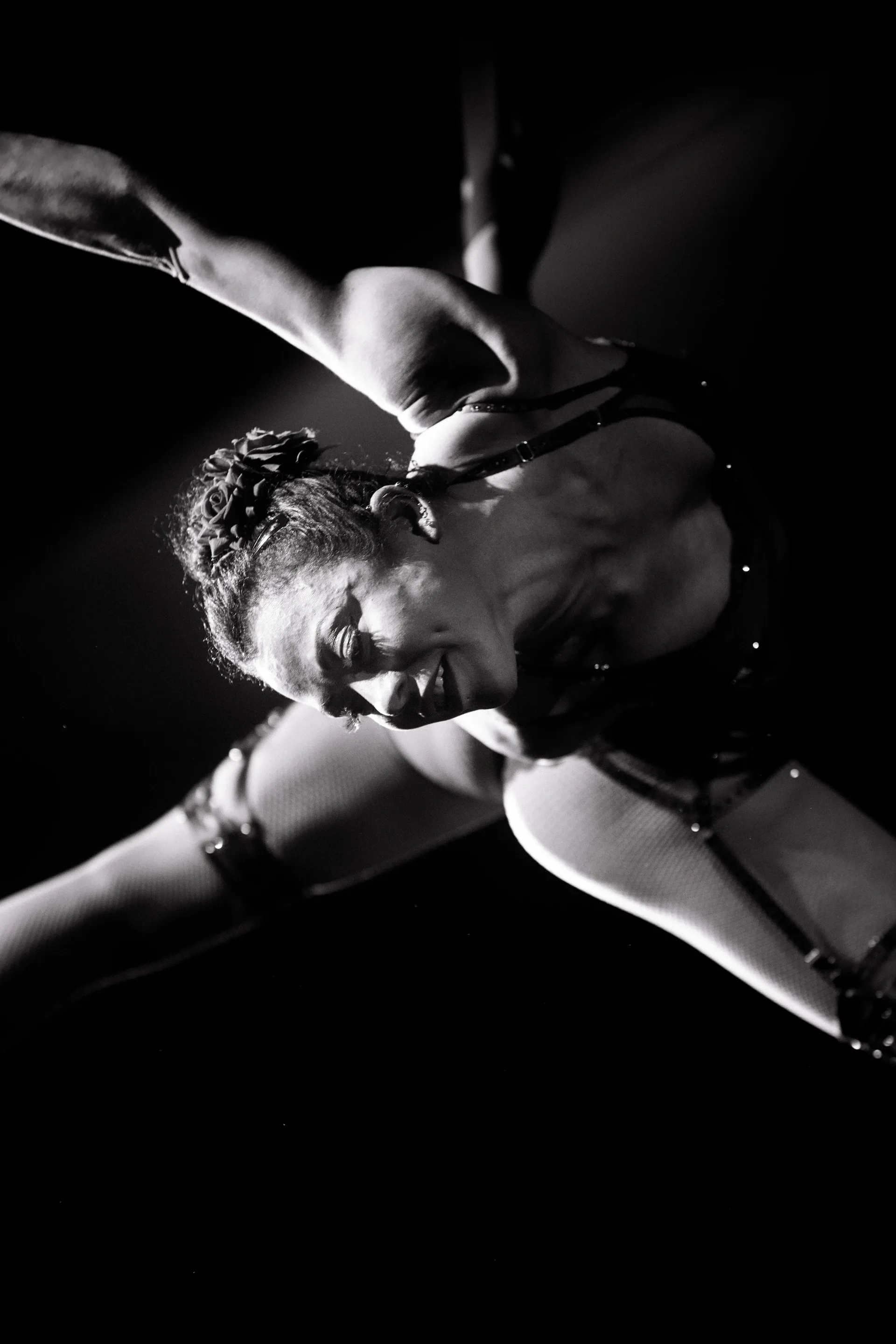 Aerialist hangs horizontally with one arm extended toward the audience.
