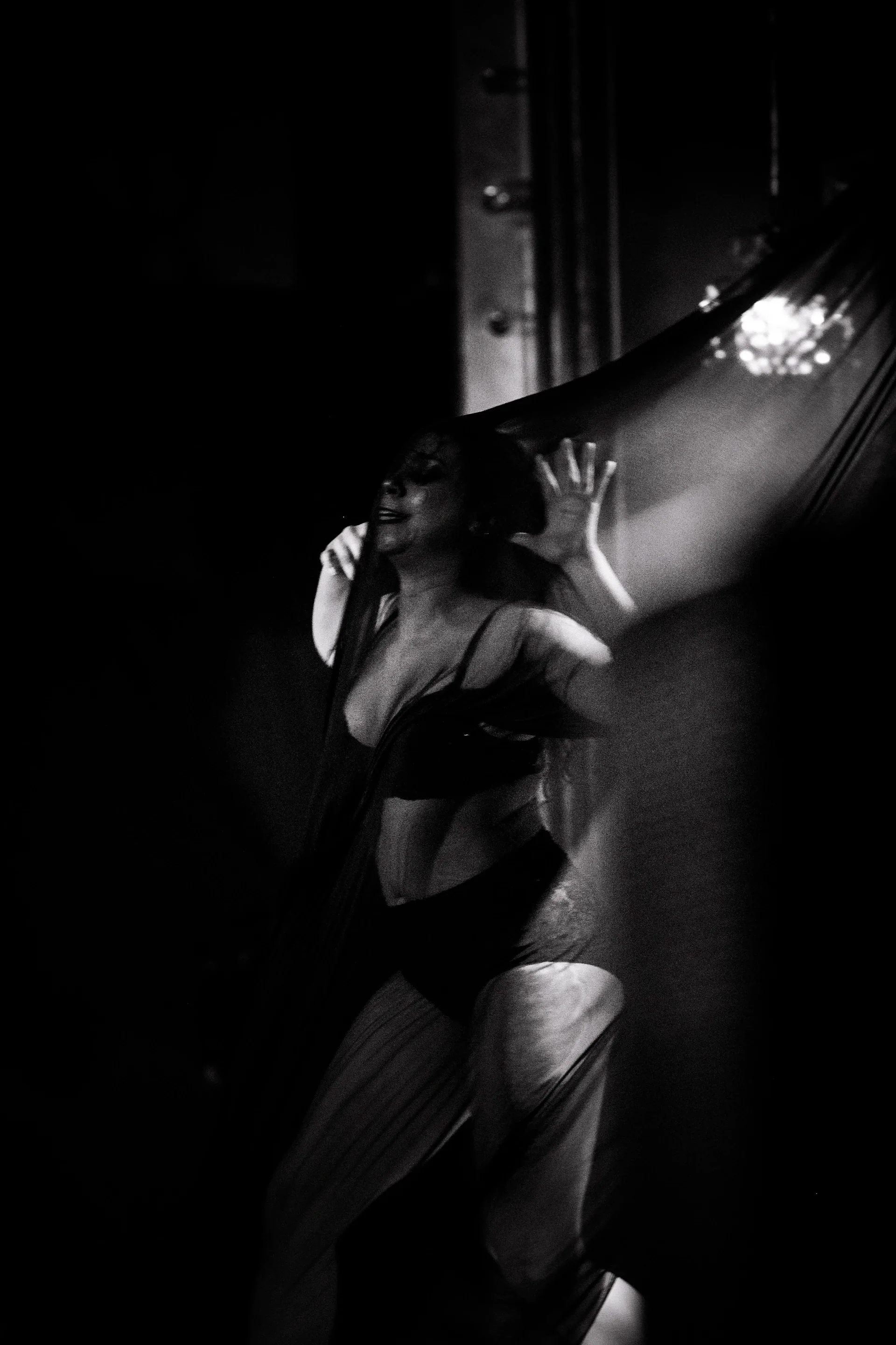 Two stage performers hold each other beneath angled light.