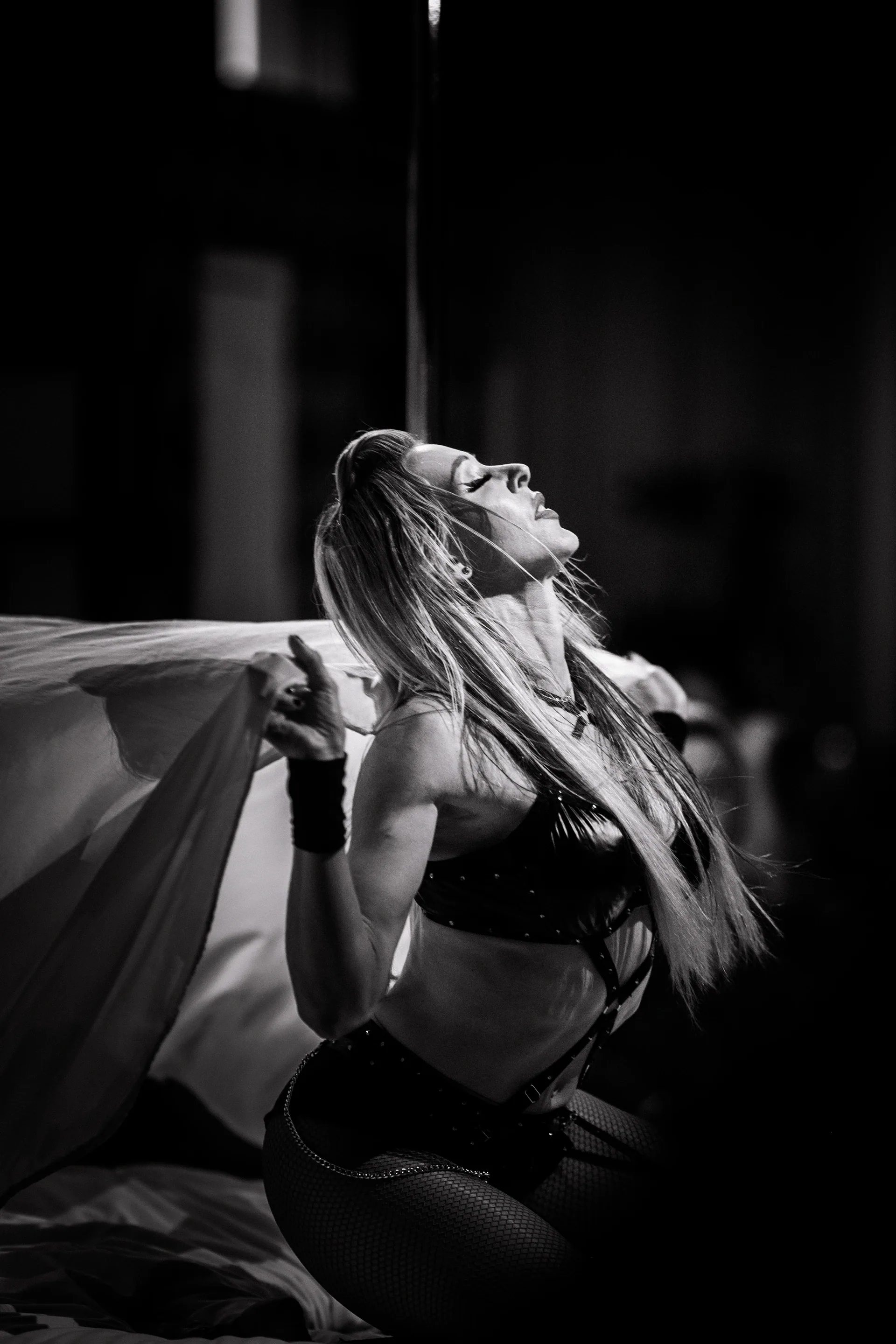 Seated performer leans backward with loose fabric spread behind.