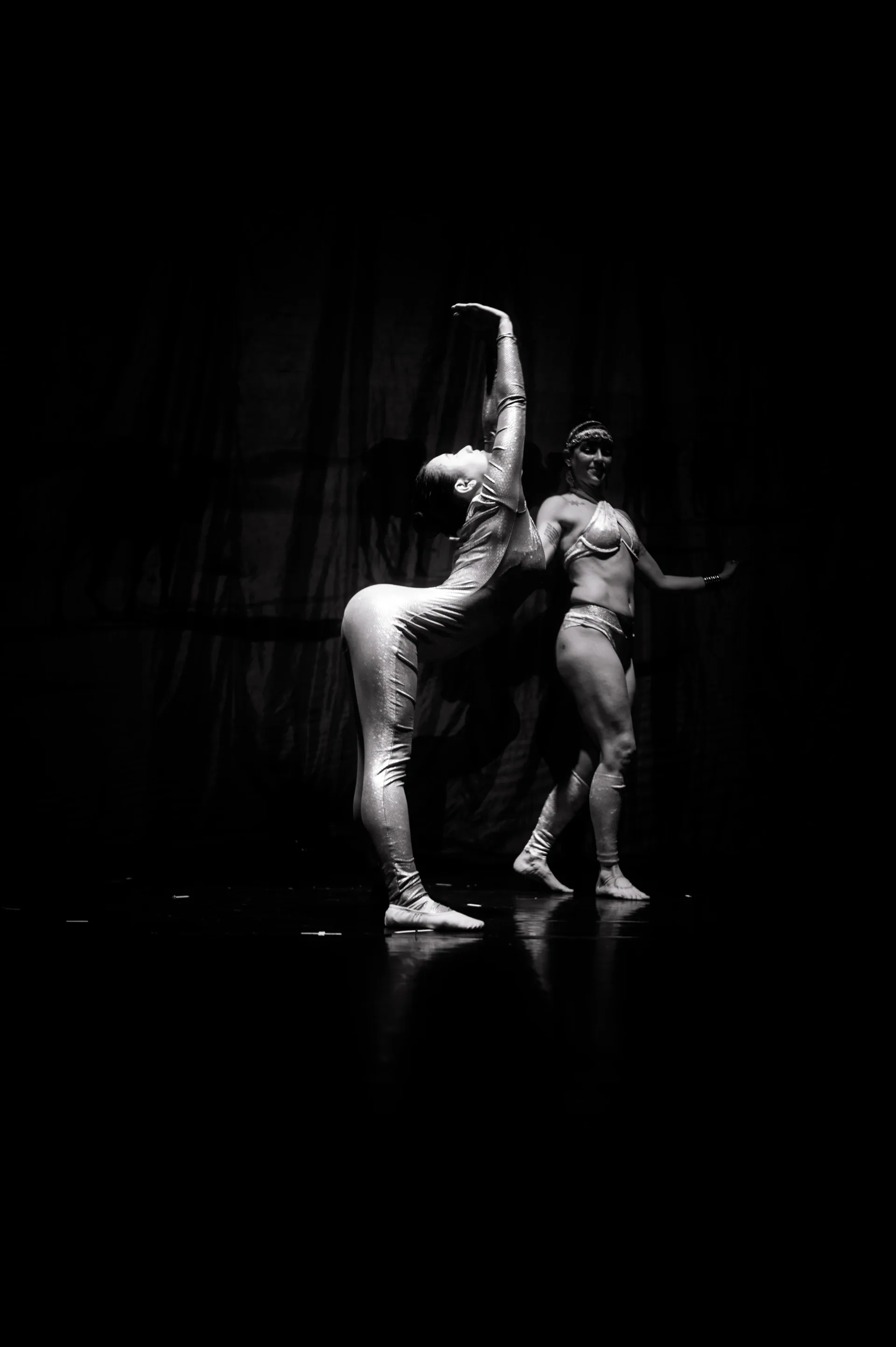 Two performers pose together, one raising a leg vertically.
