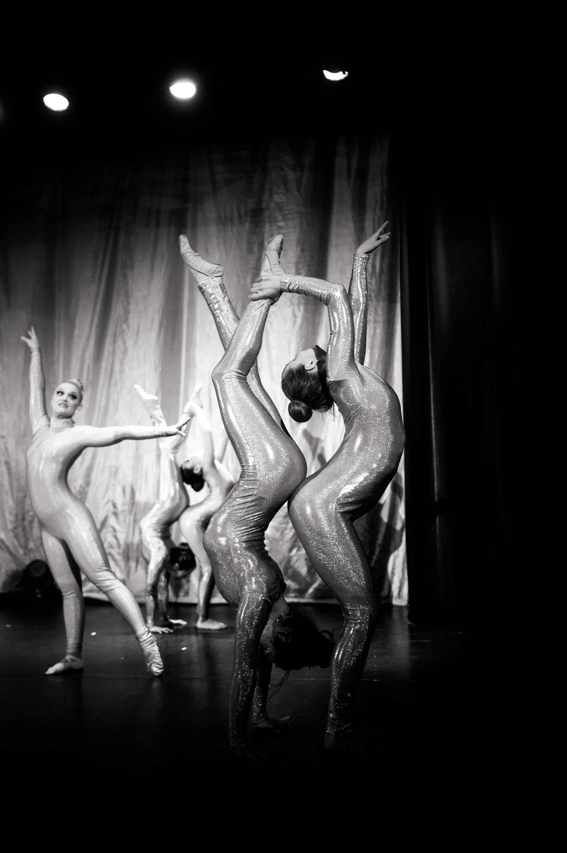 Ensemble of contortionists forms a row of curved handstands.