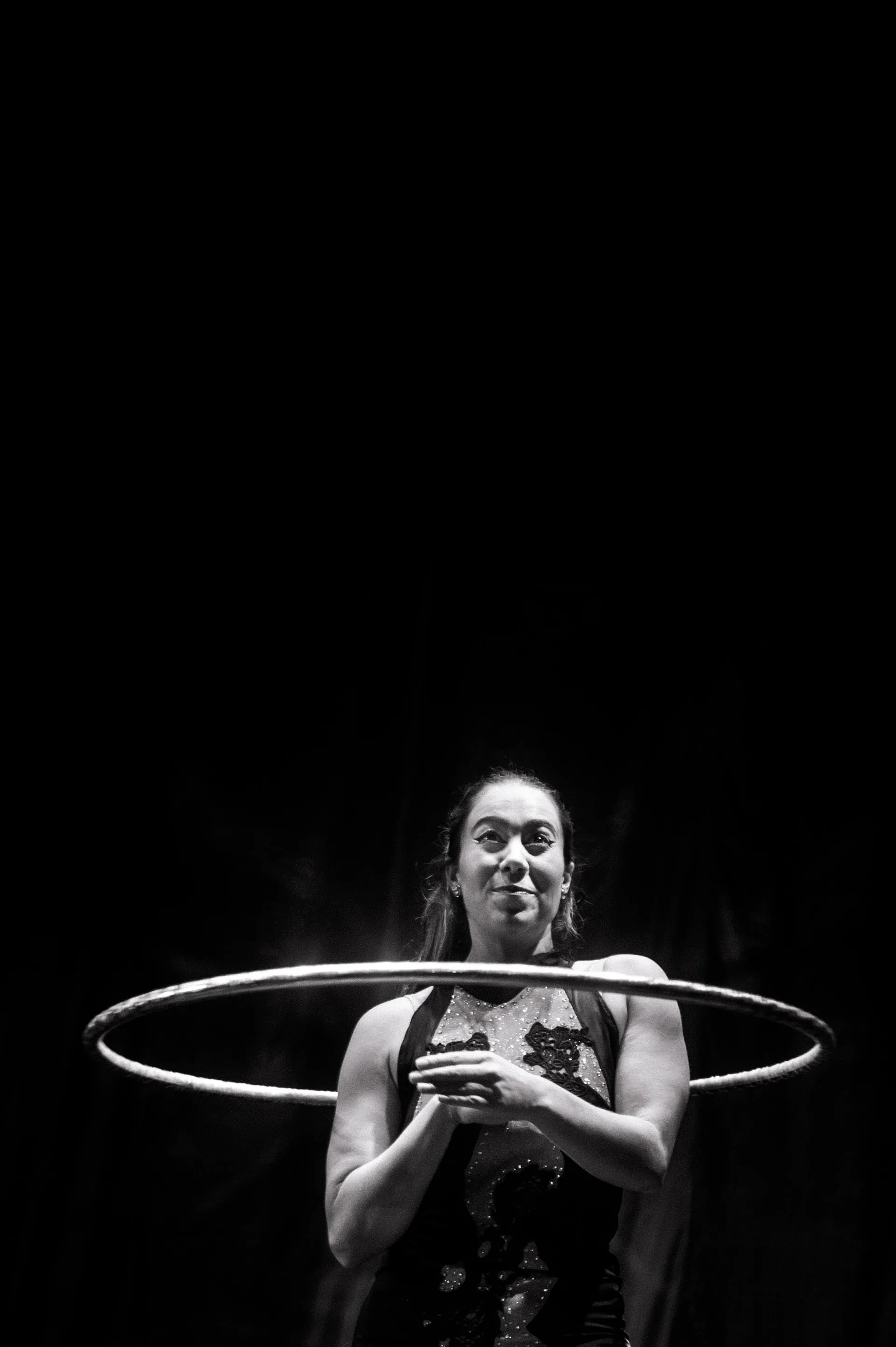 Performer stands with a hoop held horizontally around the upper body.