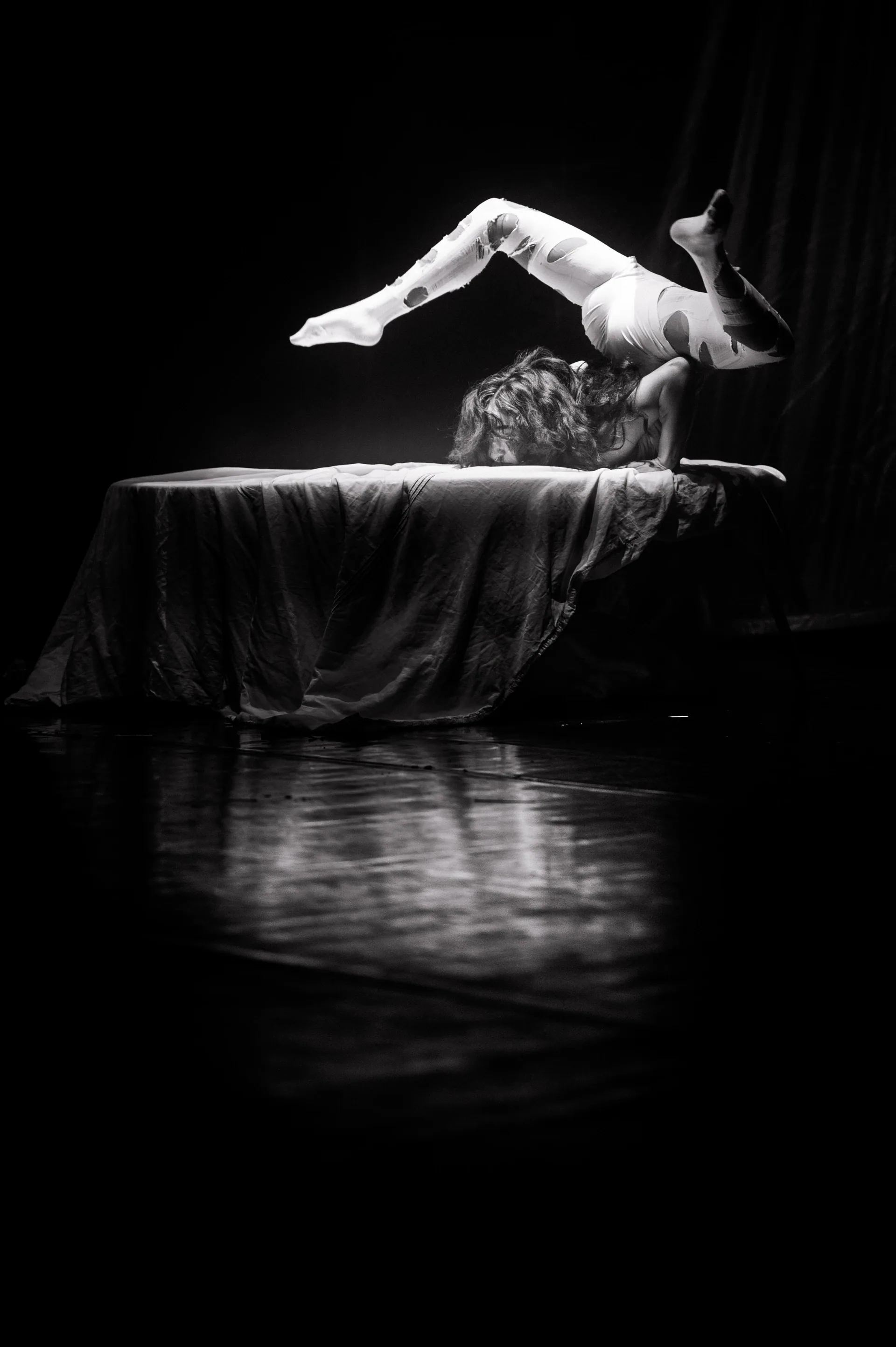 Contortionist arches backward across a raised platform.