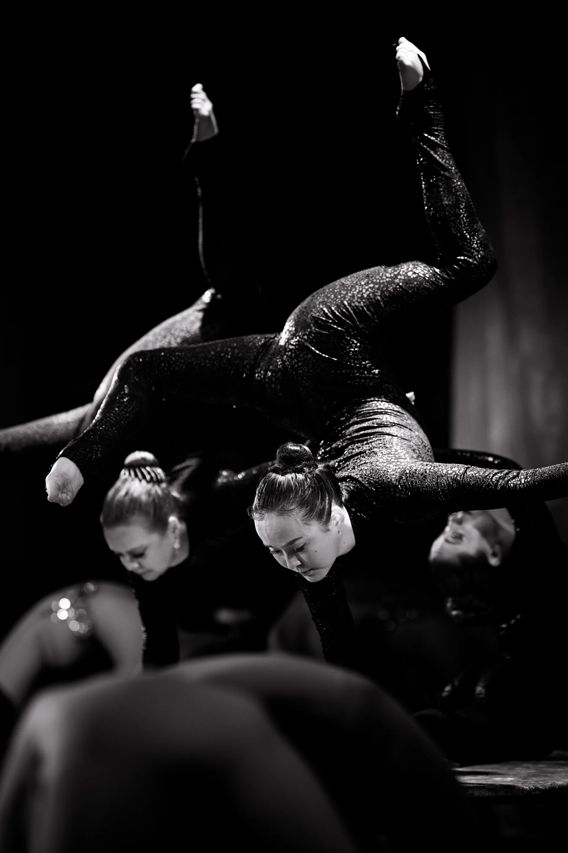 Two contortionists form a crossed balance on a platform.