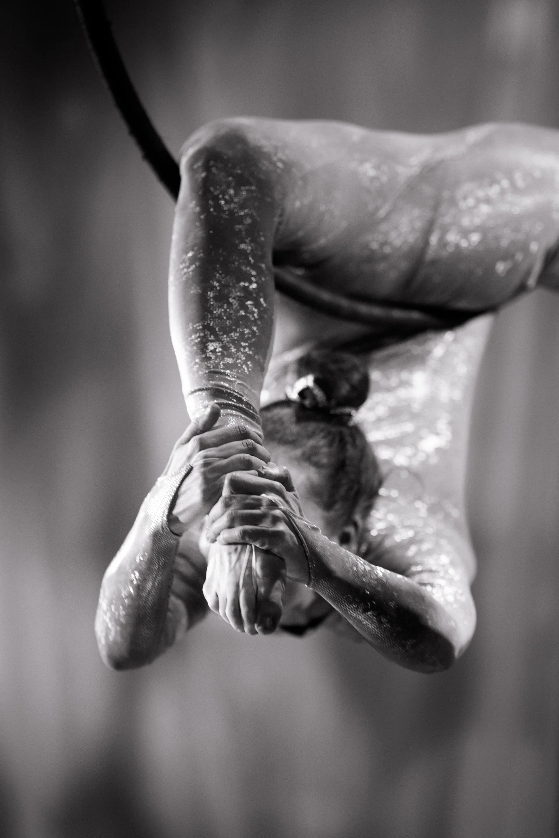 Close view of a contortionist folded backward with hands clasping the head.