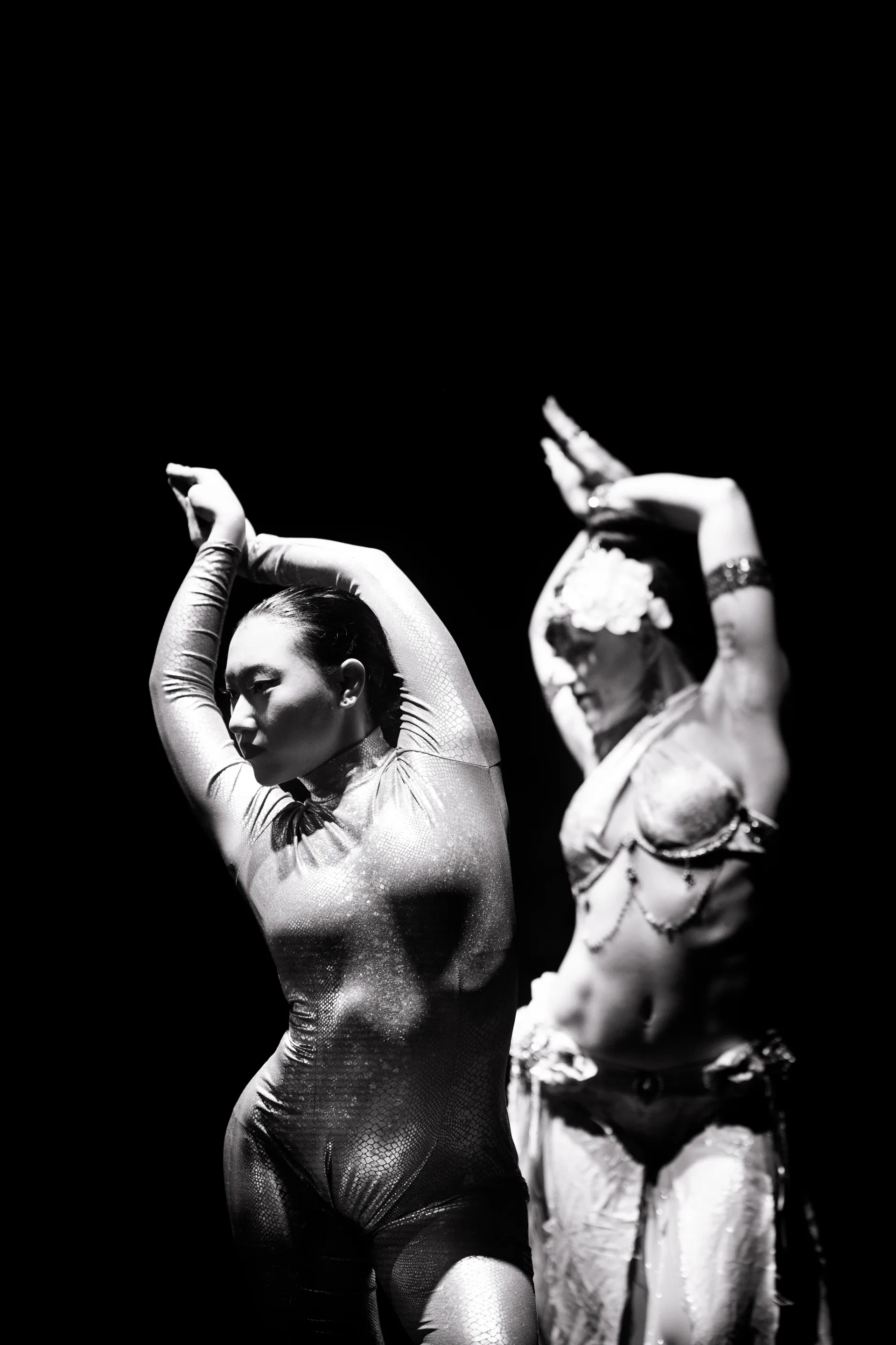 Two performers pose side by side with arms raised.
