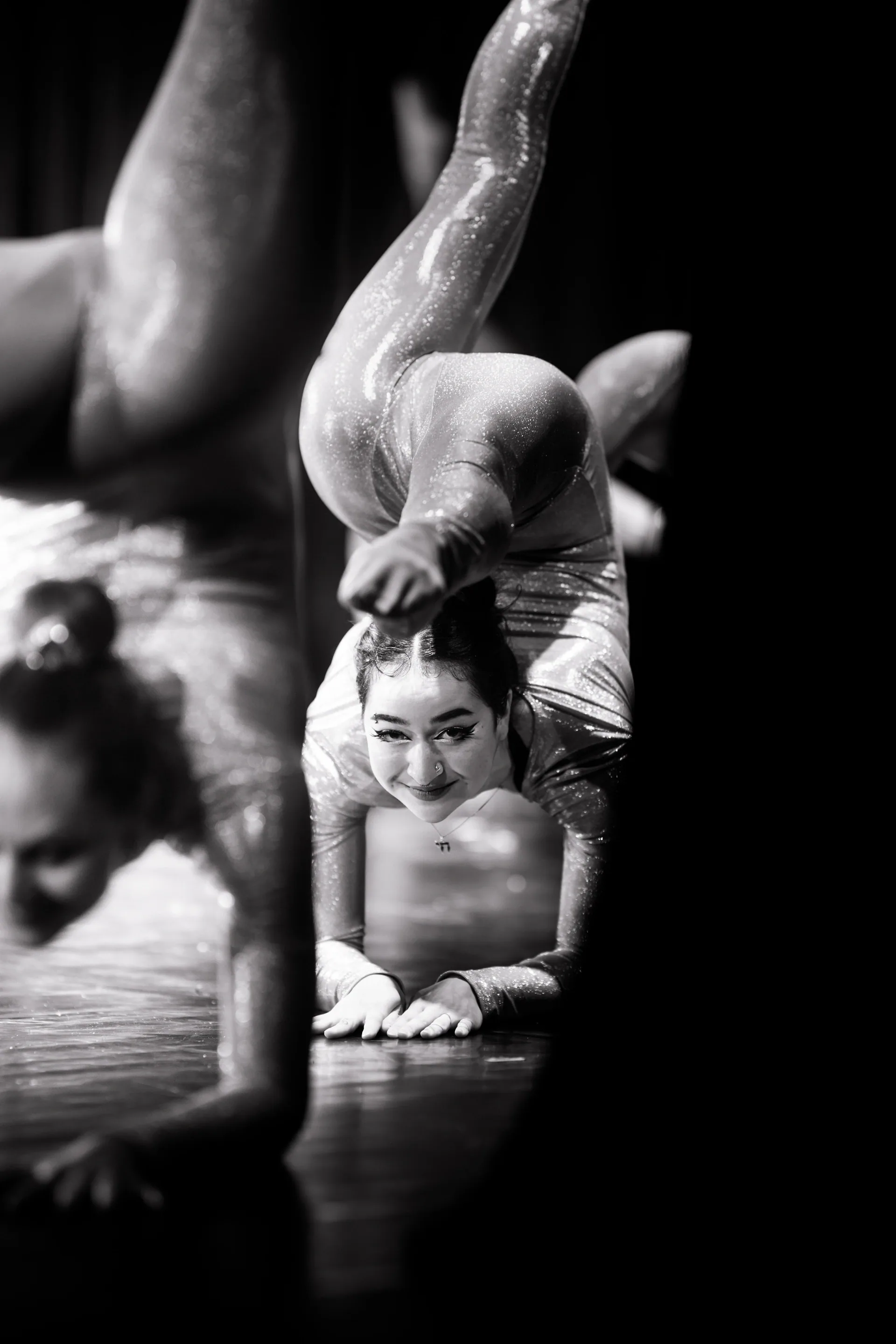 Two contortionists form a balance with one inverted above the other.