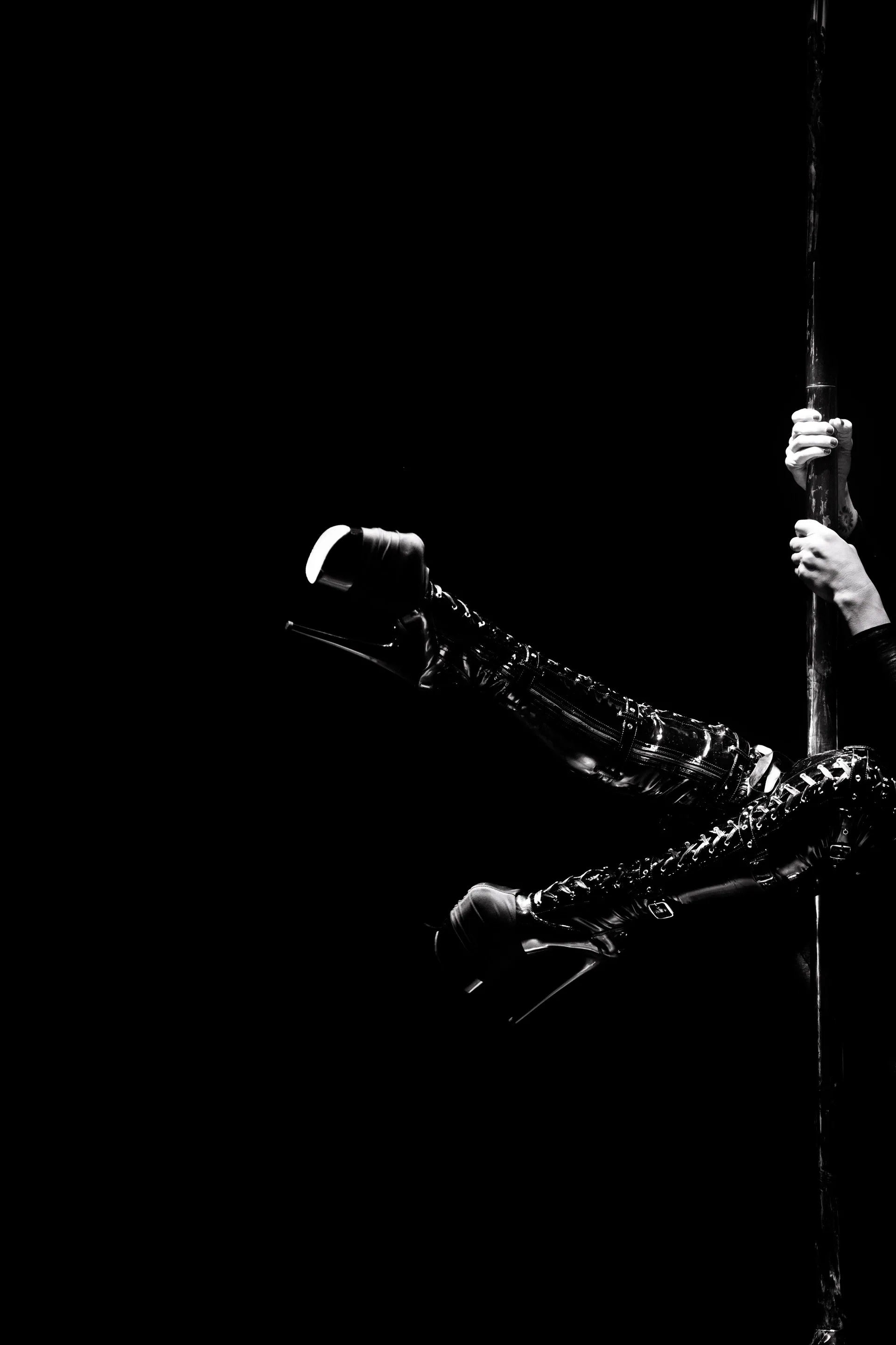 Aerialist extends horizontally from a vertical strap.