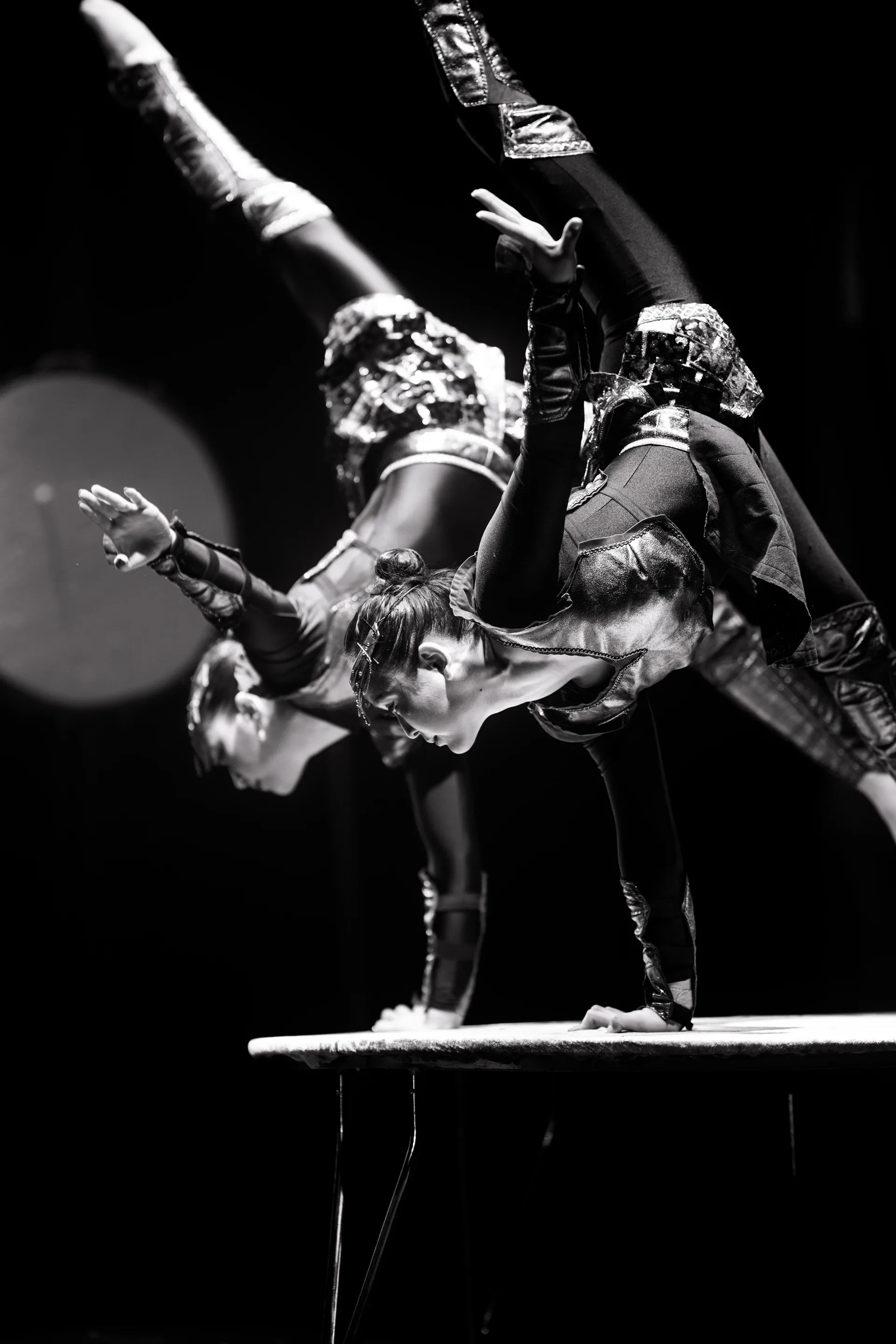Three acrobats form a stacked balance on a hand-balancing platform.