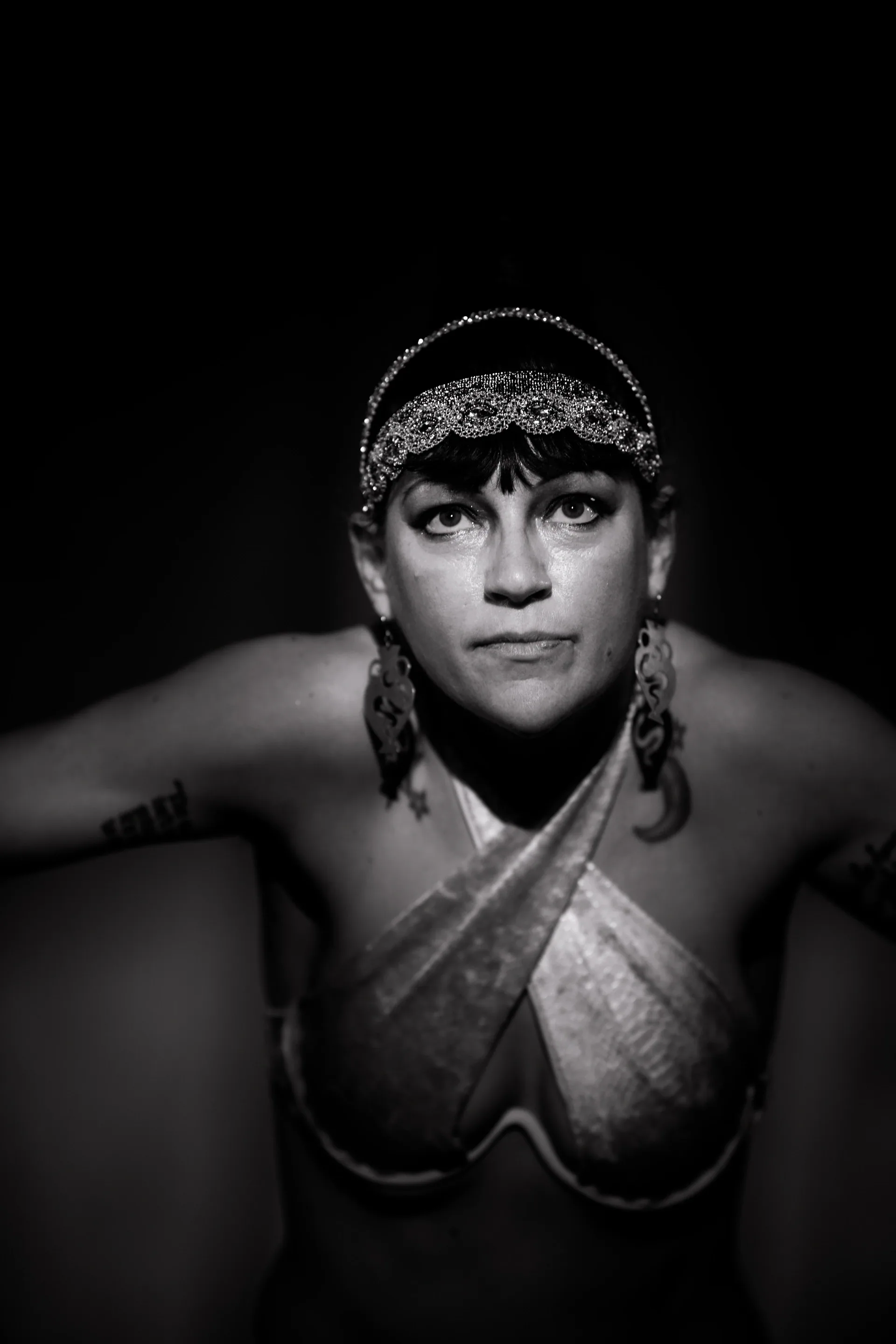 Performer wearing a beaded headband looks upward toward the camera.