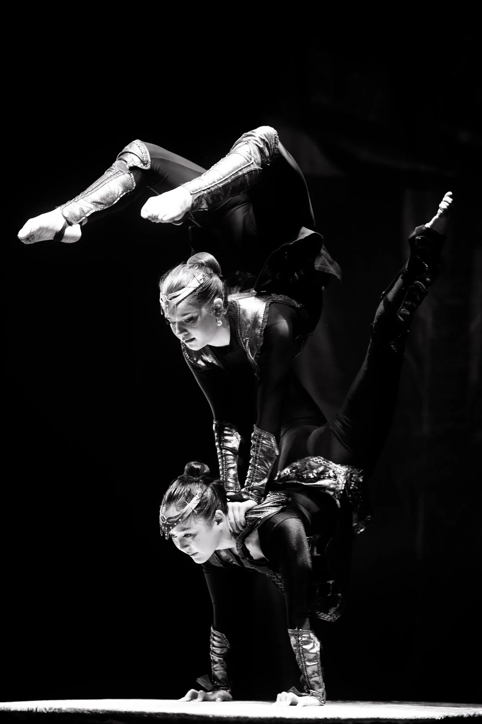Three contortionists form a vertical stack of handstands.